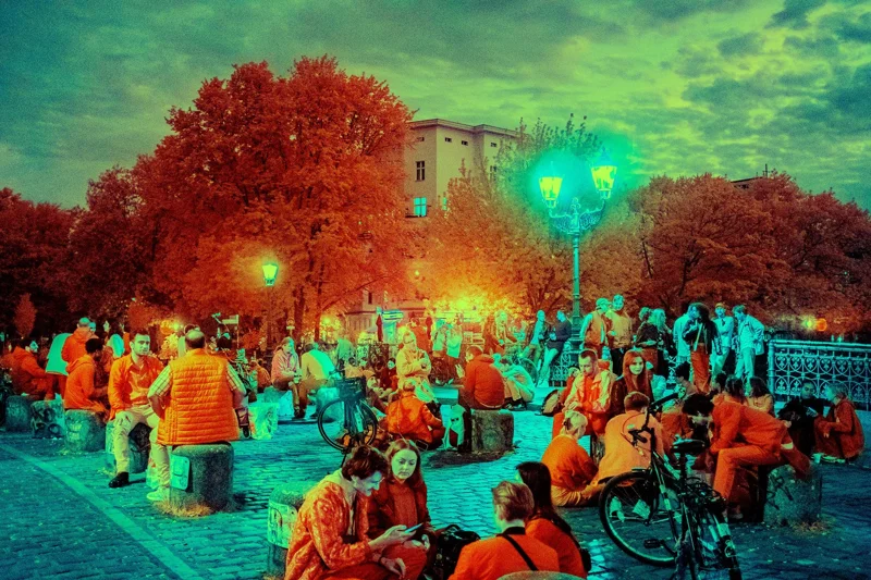 Photographie d’art infrarouge d’André Wagner: Des personnes sont assises ou debout en petits groupes sur le pont, parmi les vélos, les bornes et la balustrade ouvragée — Admiral Bridge.
