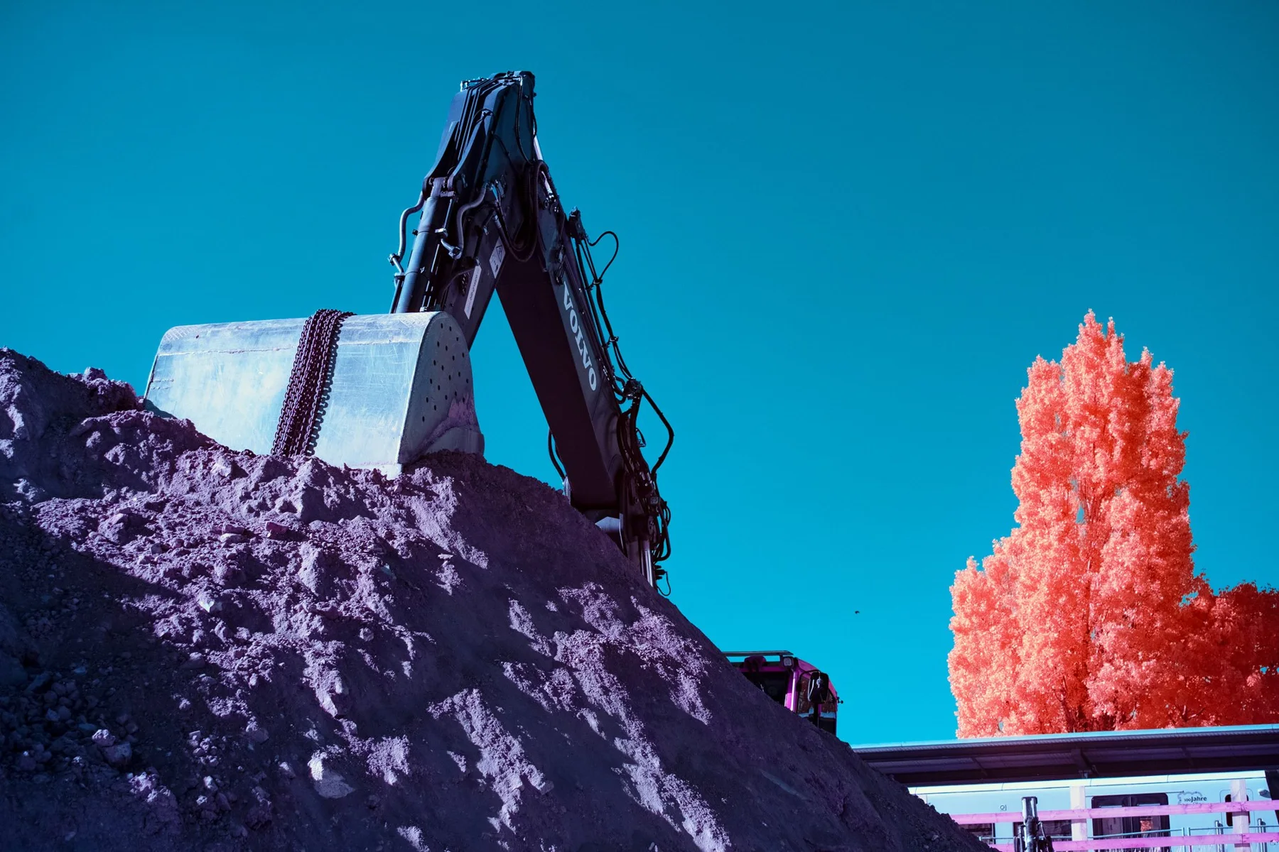 Pelleteuse devant un paysage aux couleurs infrarouges.