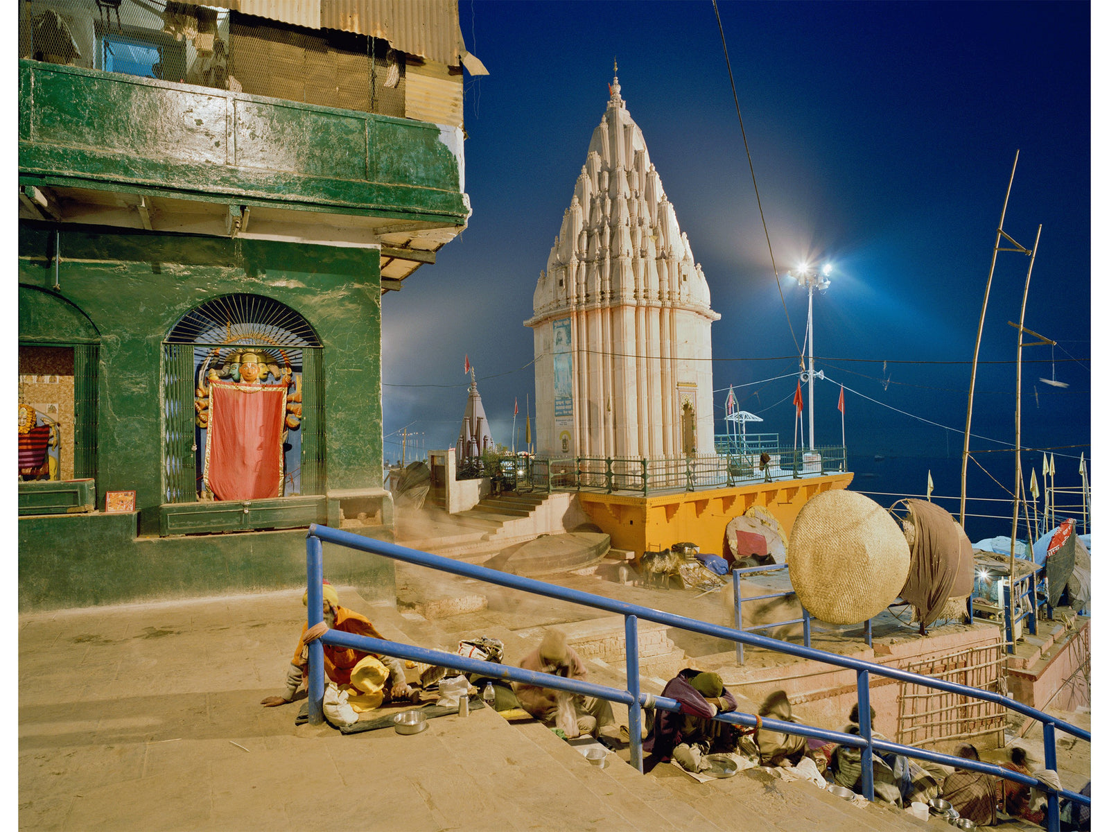 Fine art photography by André Wagner: A pale temple tower rises against a deep blue sky — Benares - sleeping gods, Indien.