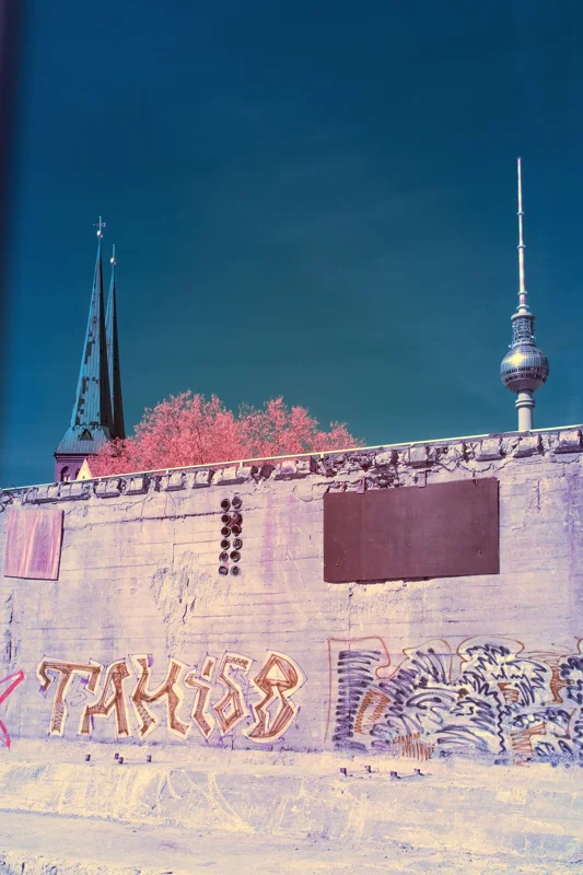 Photographie d’art infrarouge d’André Wagner: Une surface de béton couverte de graffitis occupe la partie inférieure du format vertical — Berlin — Urban Palimpsest.