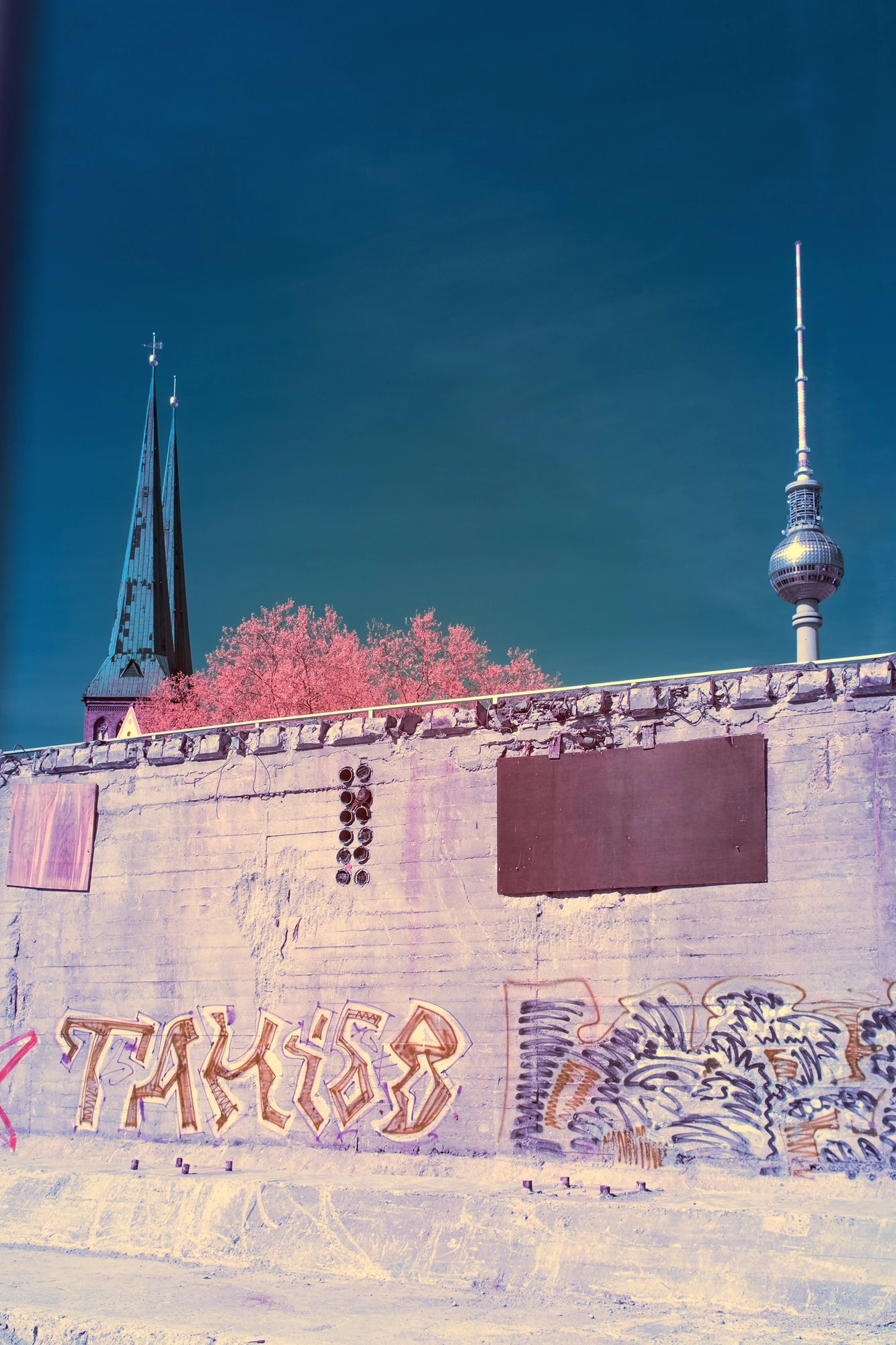 Photographie d’art infrarouge d’André Wagner: Une surface de béton couverte de graffitis occupe la partie inférieure du format vertical — Berlin — Urban Palimpsest.