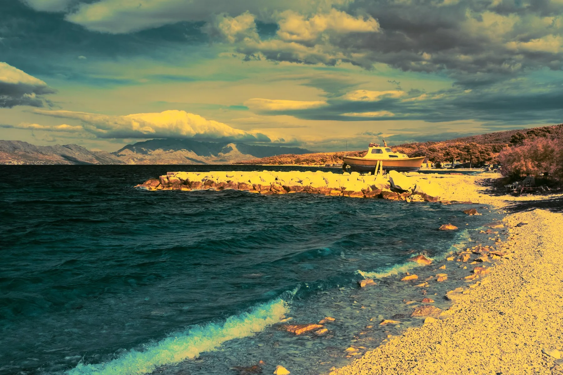 Baie avec plage et vagues sous un ciel nuageux.