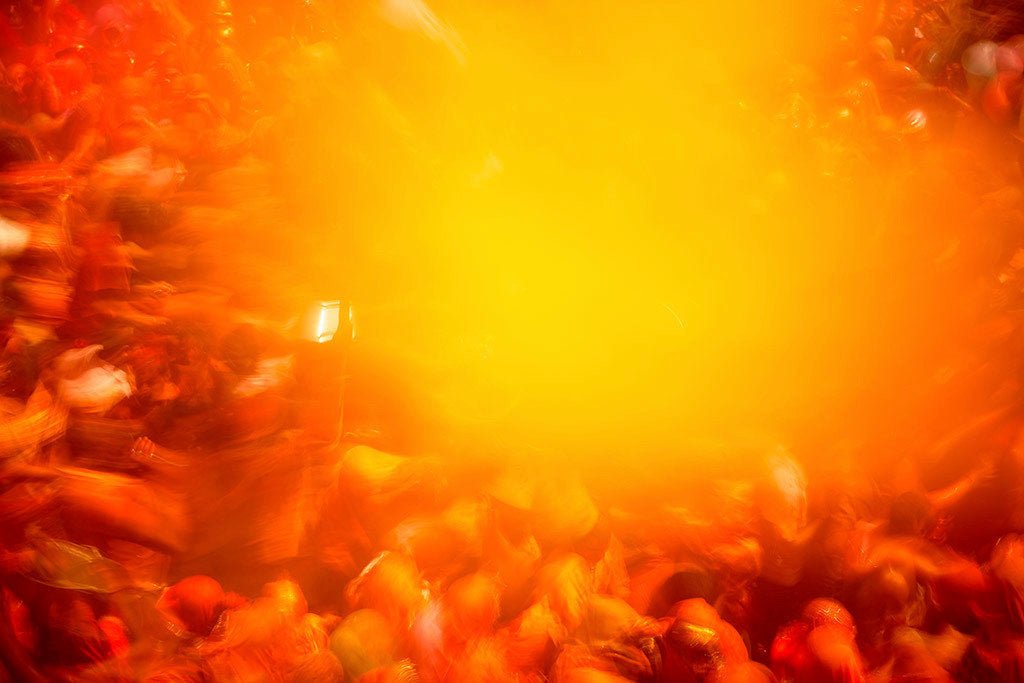 Fine art photography by André Wagner: A dense crowd surrounds a large yellow orange cloud — Color Bomb, Indien.