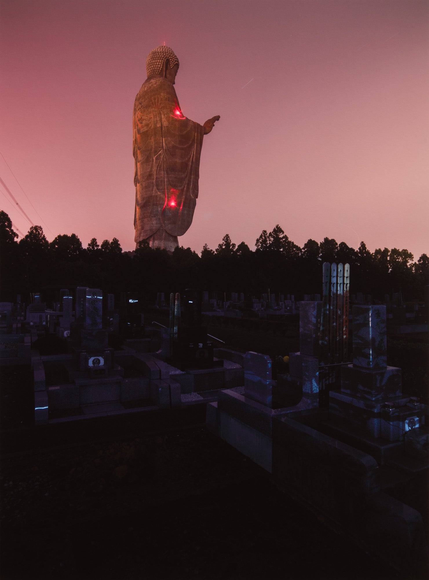 Photographie d’art d’André Wagner: Une grande figure debout dépasse une frange sombre d’arbres — Daibutsu at night, Japan.