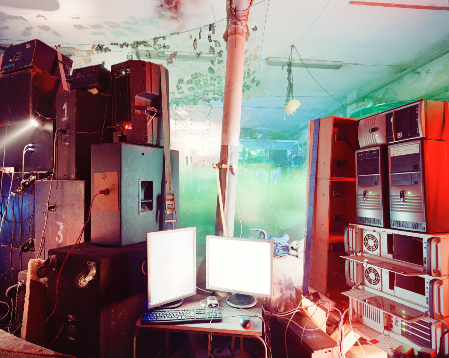 Fine art photography by André Wagner: Speakers, equipment cases and two bright screens fill a technical interior — Dj Set, Deutschland.
