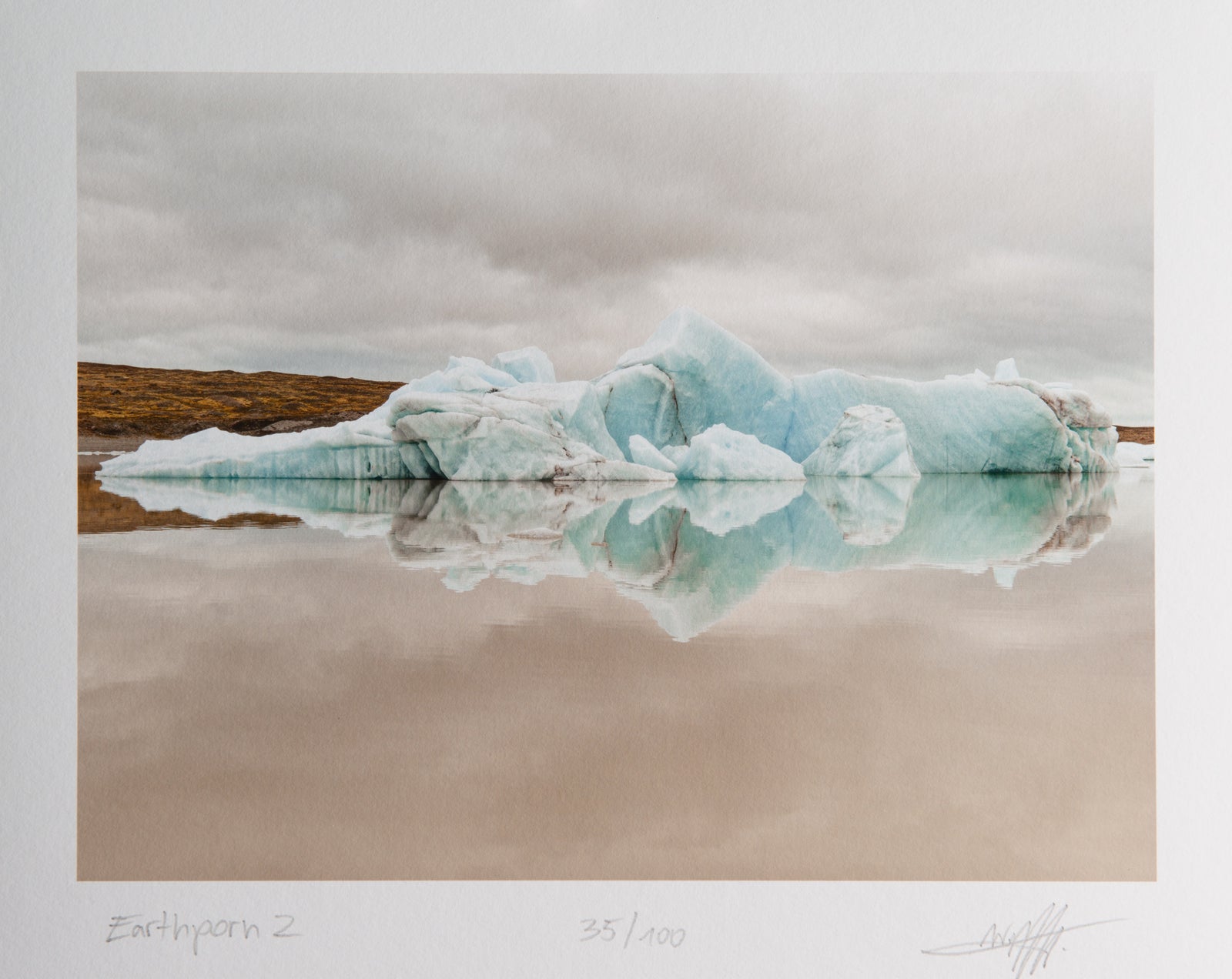 Fine art photography by André Wagner: A low broken ice form lies before brown shore — Earthporn 2, Island.