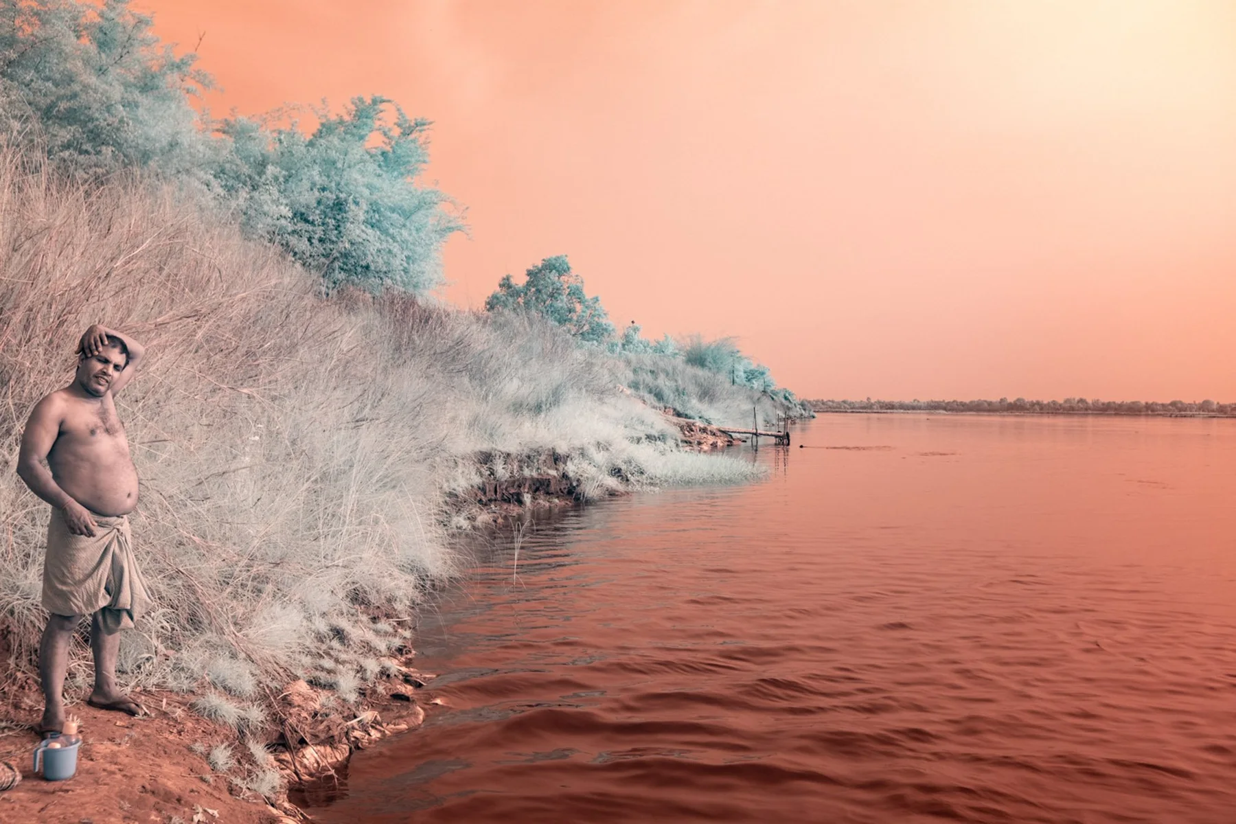 Un homme sur la rive d’une rivière orange.