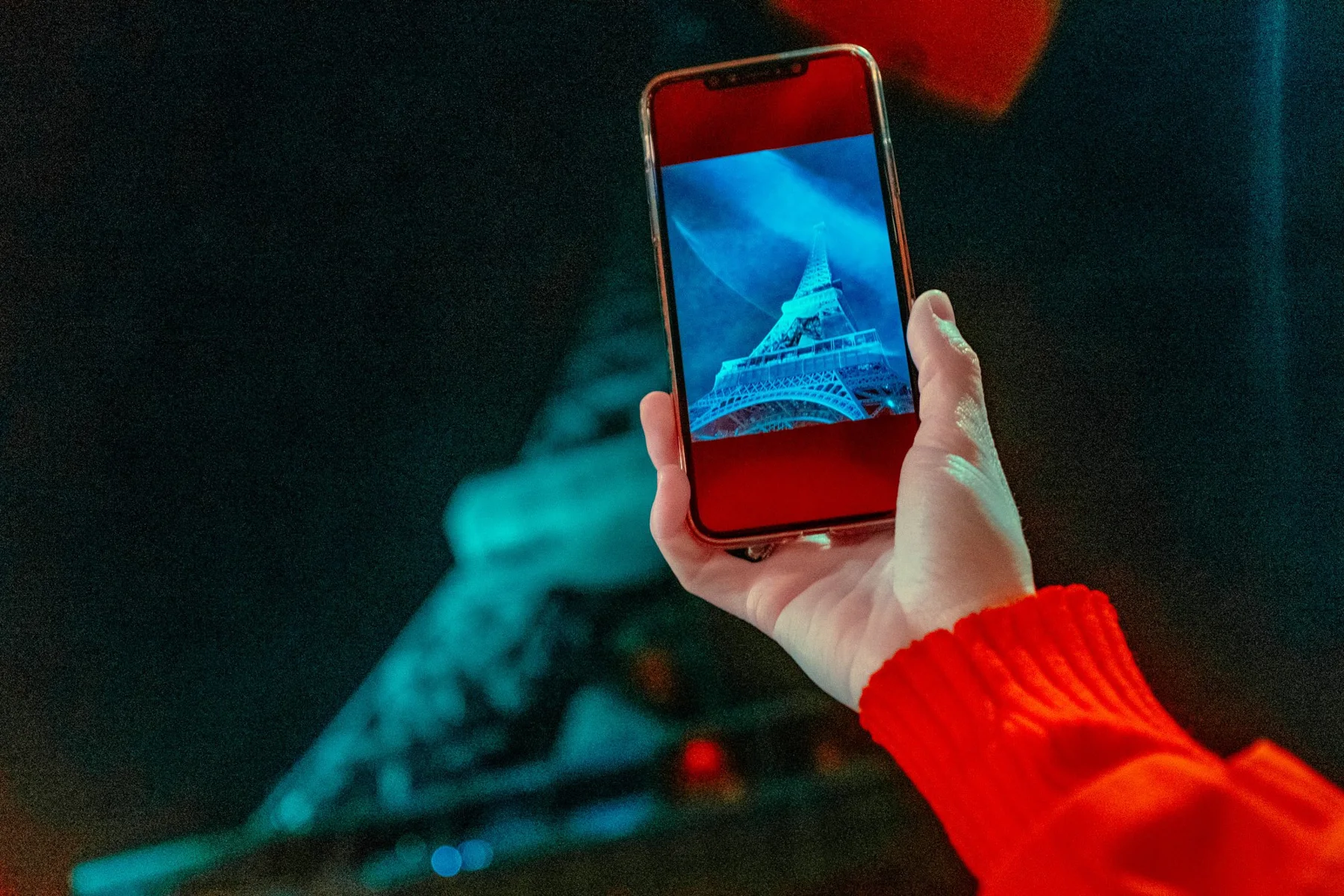 Un smartphone devant la tour Eiffel illuminée.