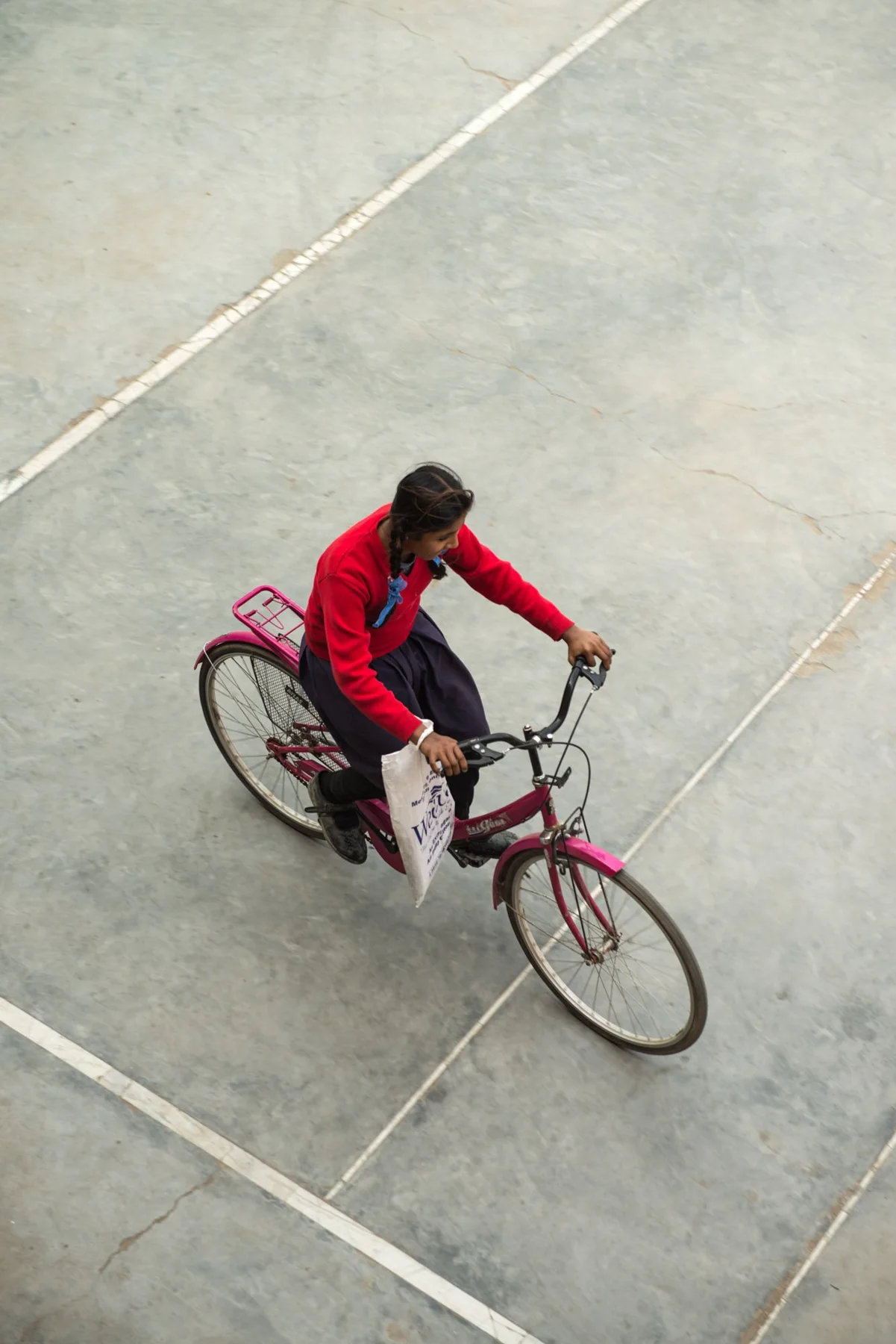 Photograph of a person in red riding a bicycle, seen from above