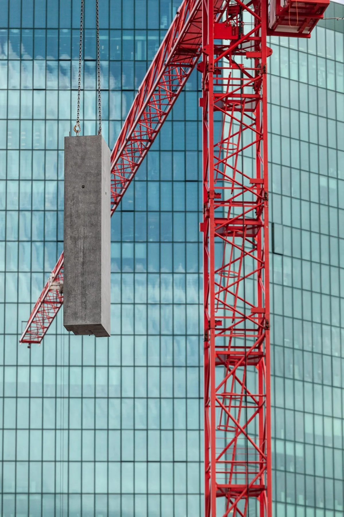 Photographie d’une grue rouge devant une façade vitrée