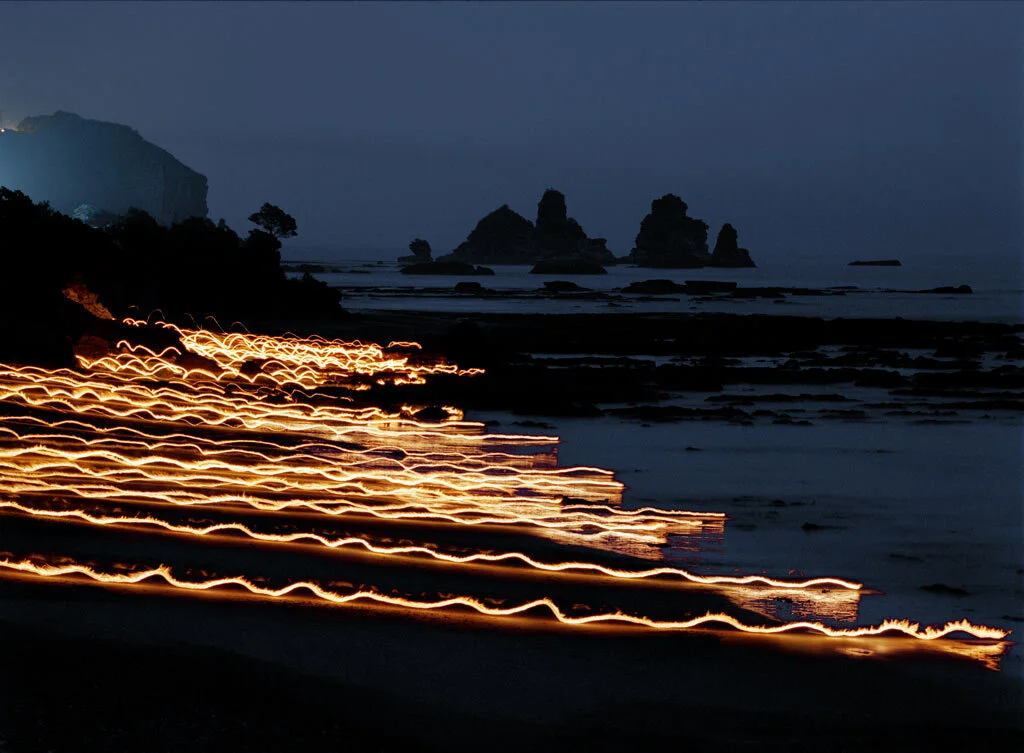 Photographie d’art de traînées lumineuses parallèles le long d’une côte sombre