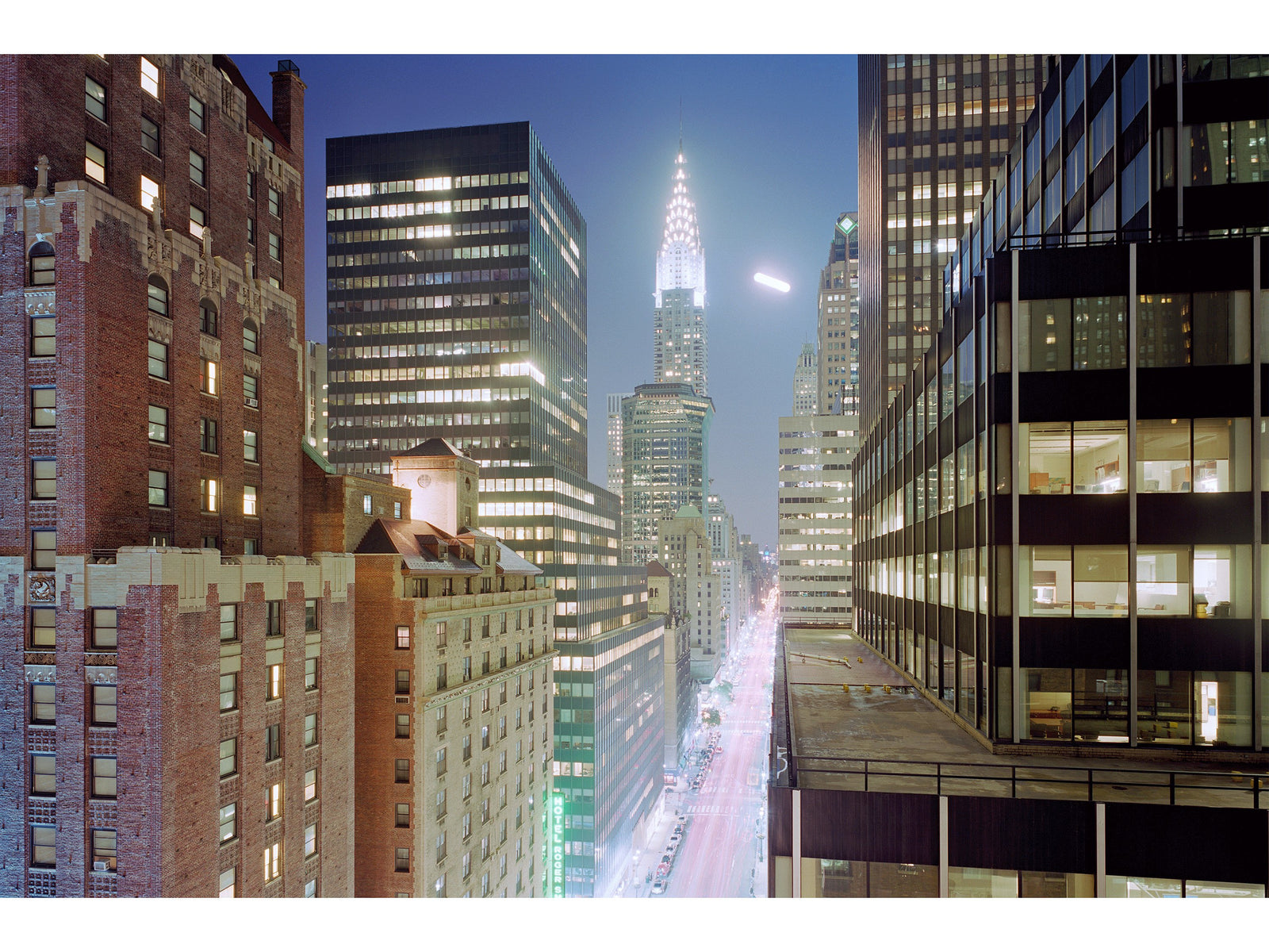 Photographie d’art d’André Wagner: Entre deux hautes rangées d’immeubles, une rue lumineuse s’enfonce dans la ville nocturne — Fullmoon in manhattan, Usa.