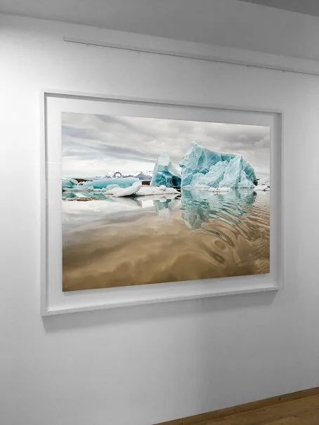 Framed photograph of waves and coastline on a white wall