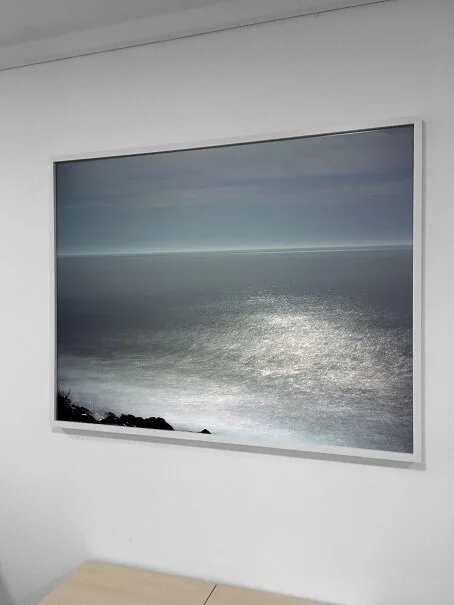 Framed seascape photograph with a calm horizon displayed on a wall