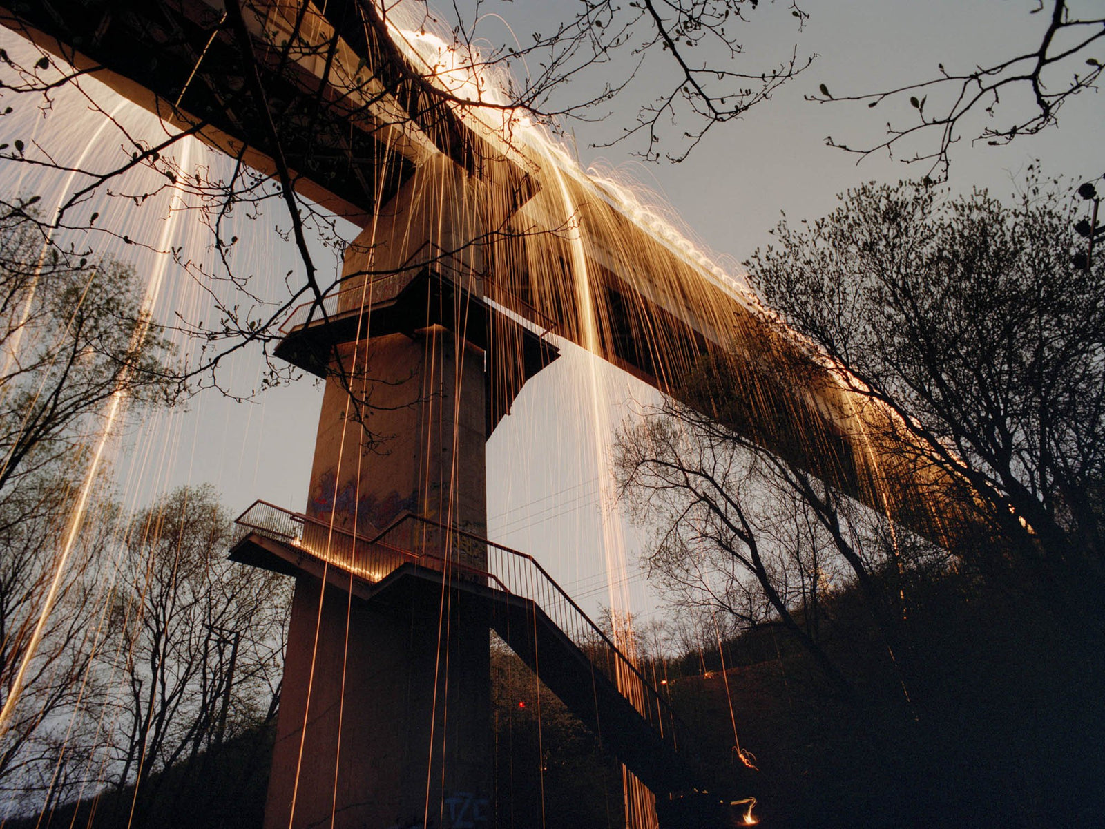 Fine art photography by André Wagner: Seen from below, a bridge crosses the sky diagonally — Golden rain, Deutschland.