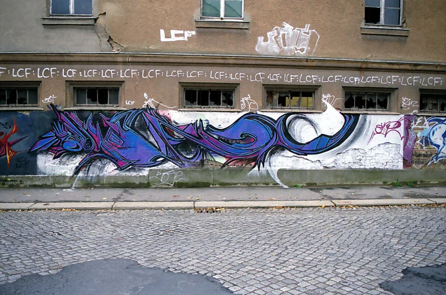 Graffiti on a building wall beside a cobbled street