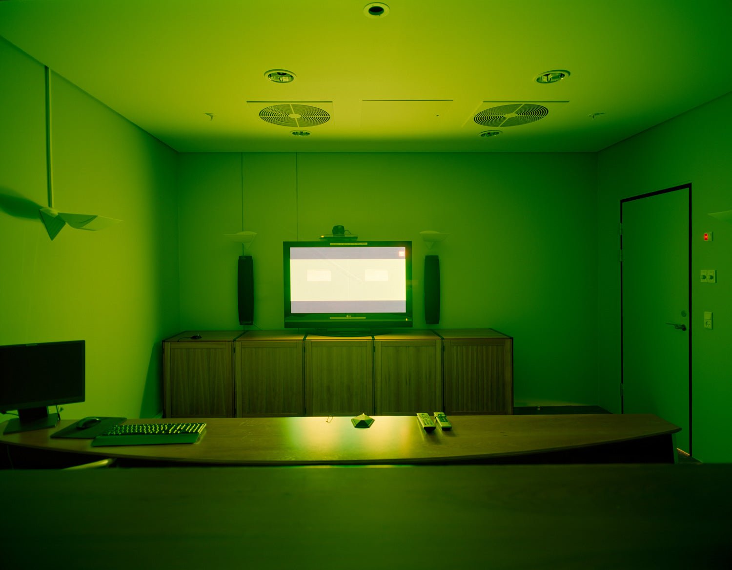 Fine art photography by André Wagner: An empty meeting room is immersed in intense green — Green Chat, Dänemark.