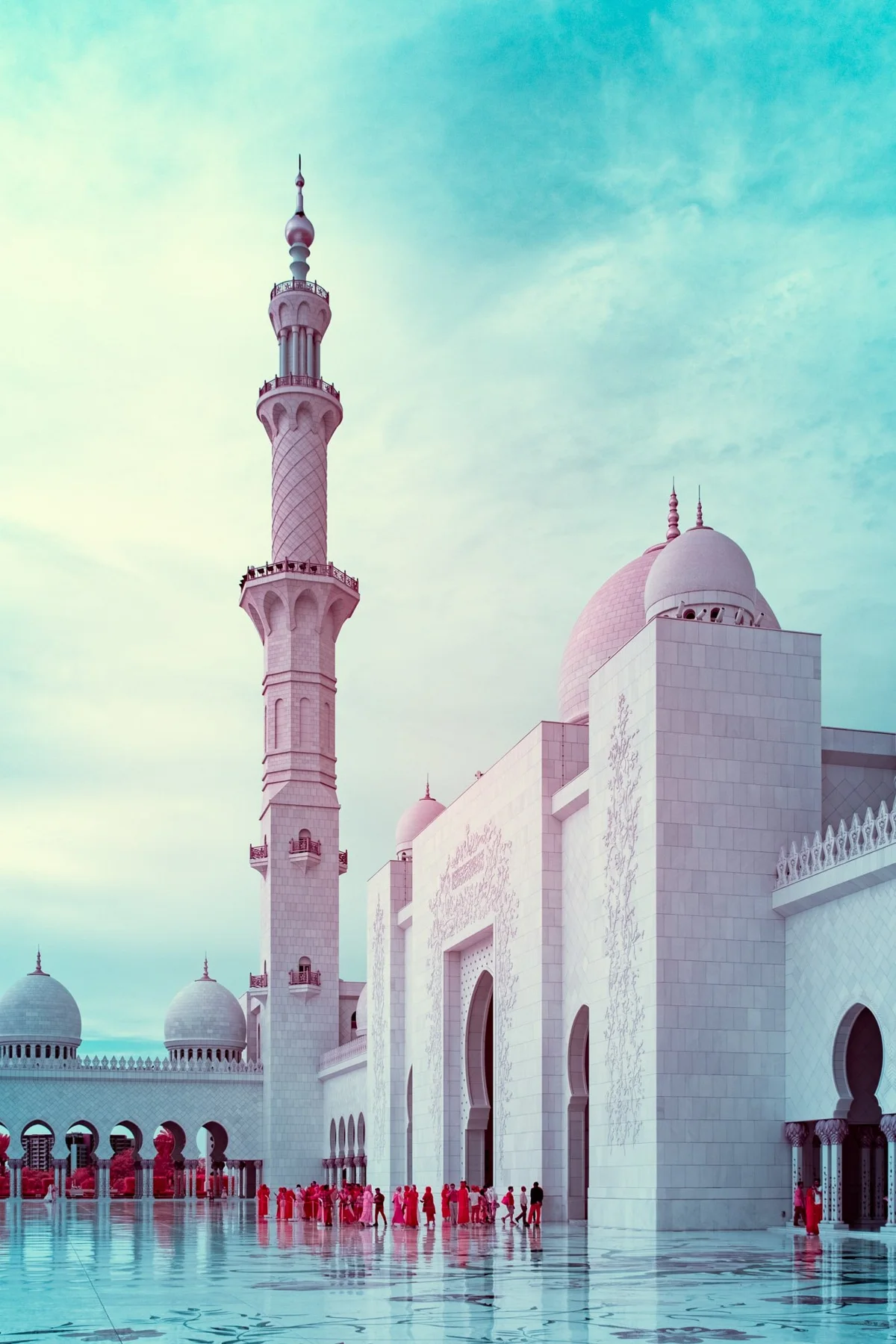 Minaret clair à côté des coupoles d’une mosquée.