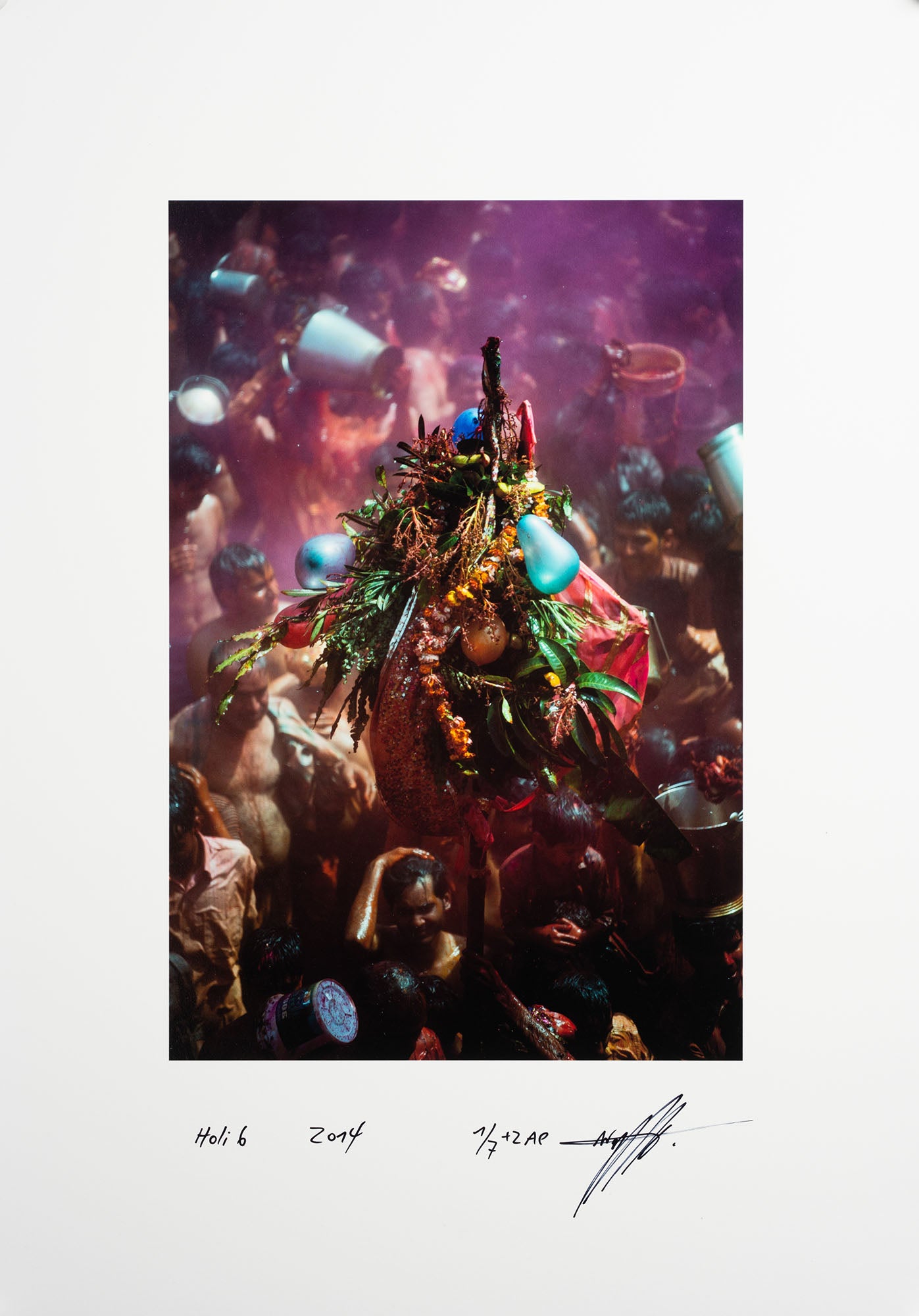 Fine art photography by André Wagner: A tall arrangement of leaves, flowers and coloured objects rises centrally within a crowd — Holi 6, Indien.