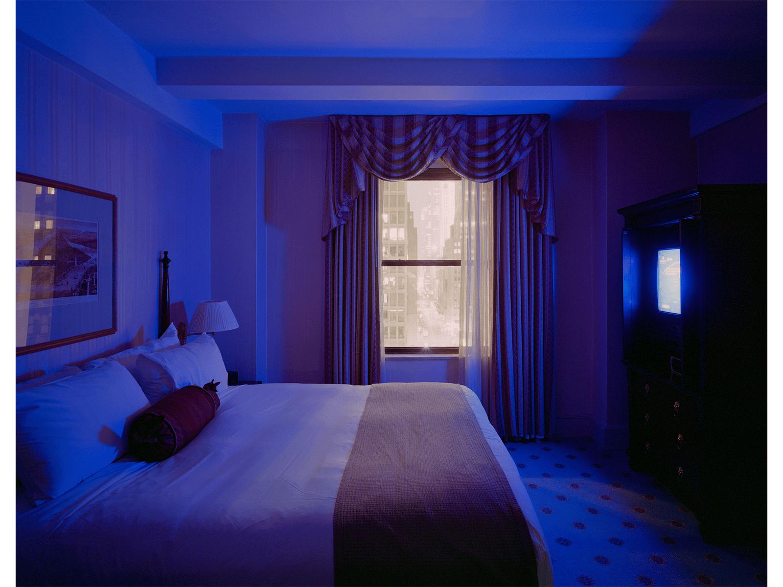 Photographie d’art d’André Wagner: Un lit fait occupe la majeure partie d’une chambre éclairée de bleu — Hot wish, Usa.