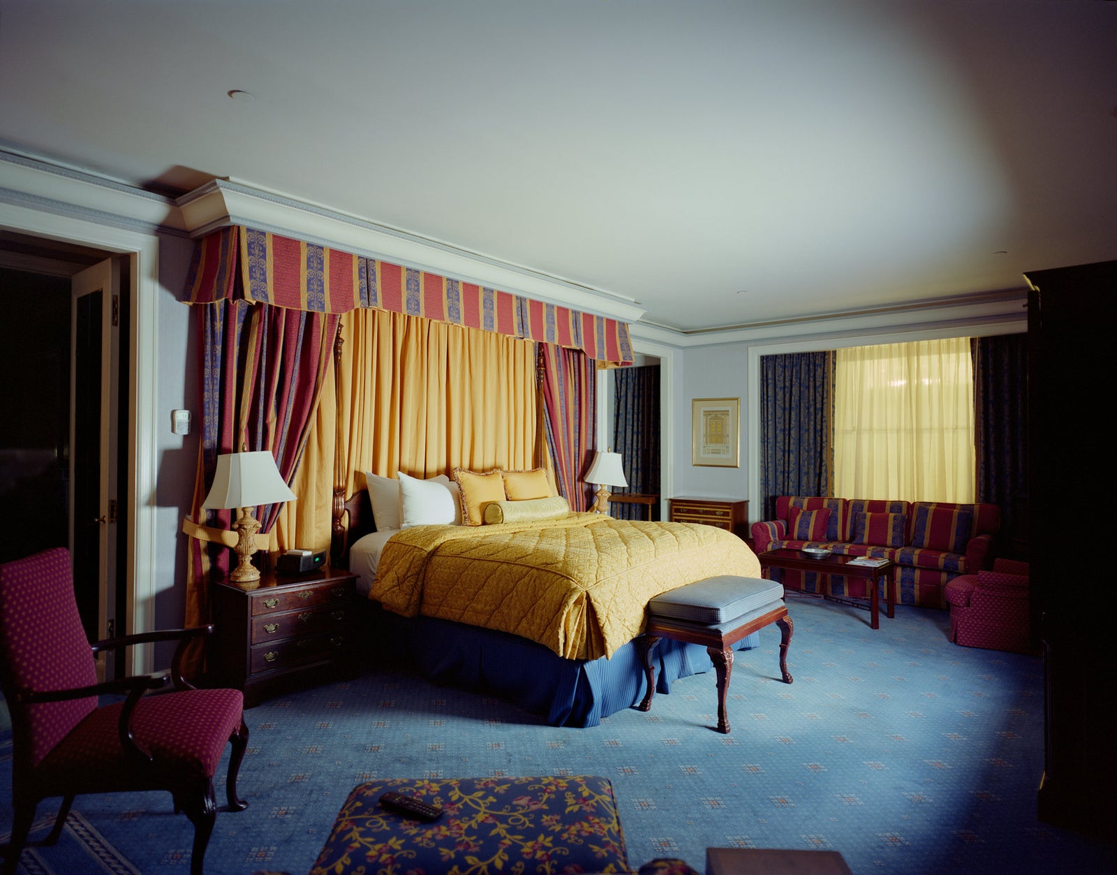 Photographie d’art d’André Wagner: Le lit occupe le centre presque de face, encadré d’un haut entourage de tissu rayé — Hotel Room in New York 2.