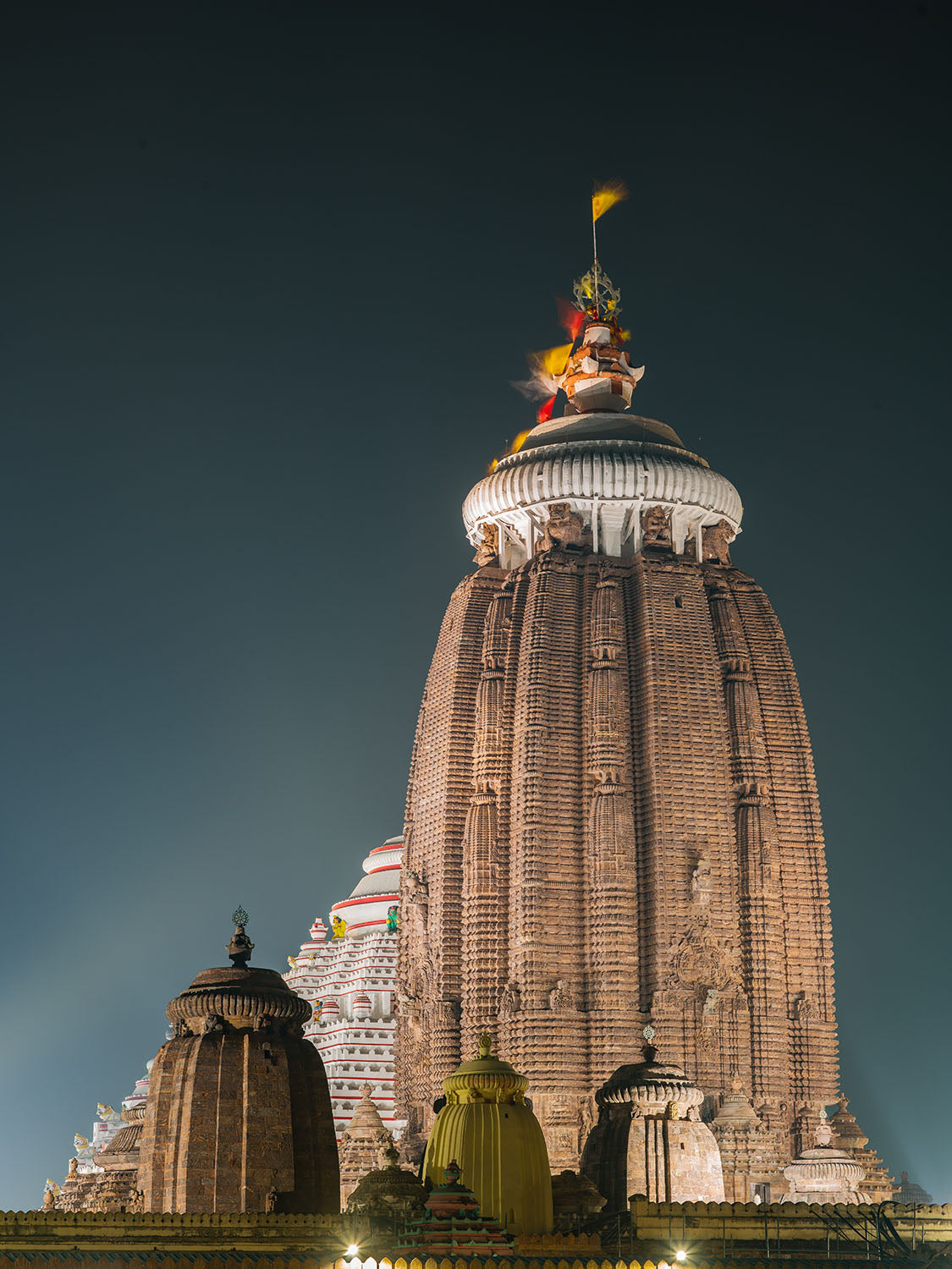 Photographie d’art d’André Wagner: Une haute tour aux articulations serrées s’élève devant un ciel sombre, bleu-vert — Jagannath temple puri, Indien.