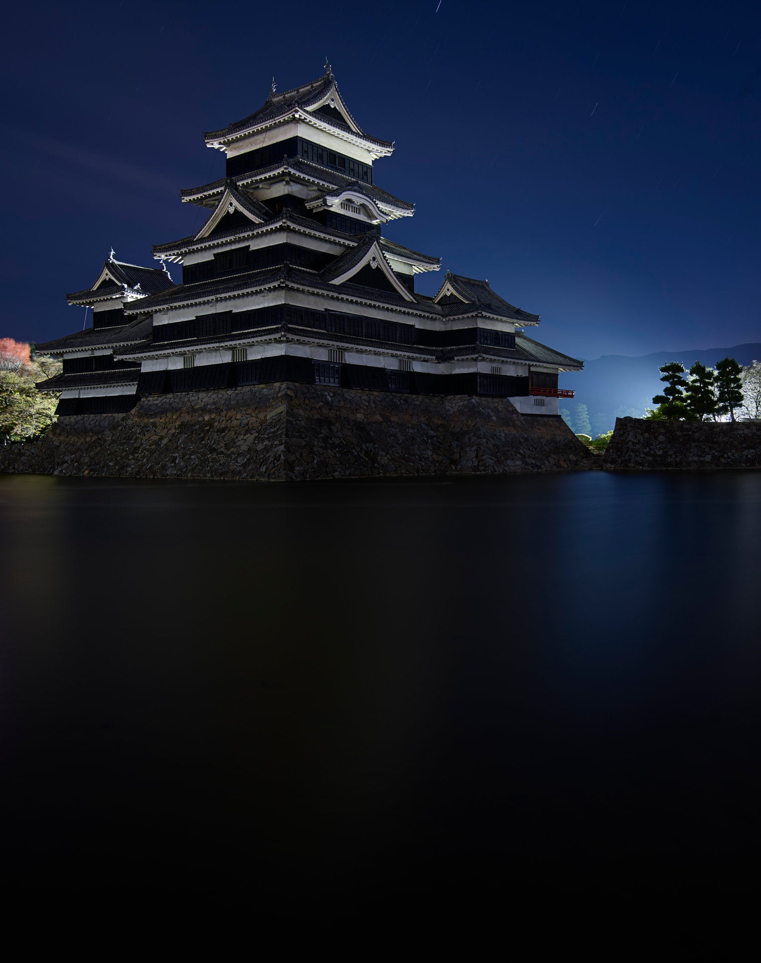 Fine art photography by André Wagner: A multilevel building with projecting roofs rises on a high stone base — Matsumoto Castle 2.