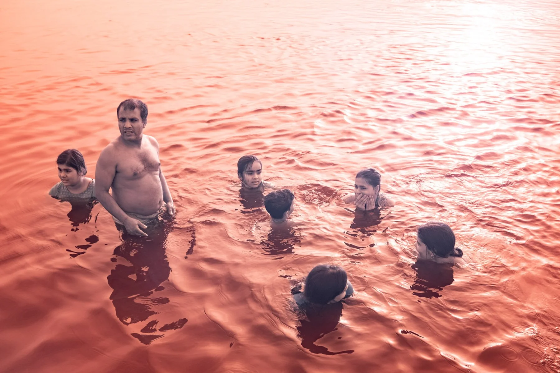 Plusieurs personnes debout dans une eau orange.