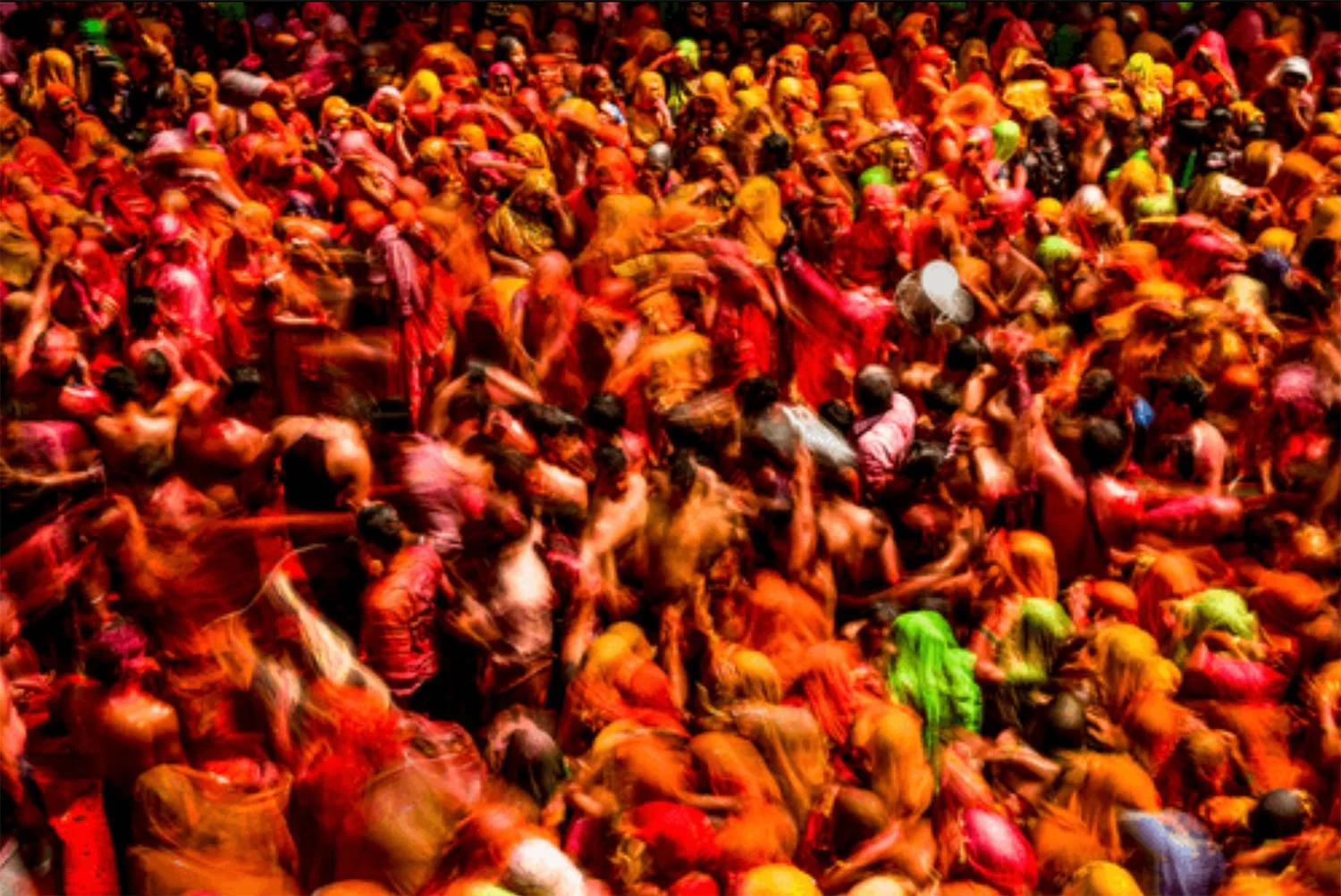 Menschenmenge beim Holi-Fest, in bunten Farben bedeckt, die auf einem Festplatz feiern.