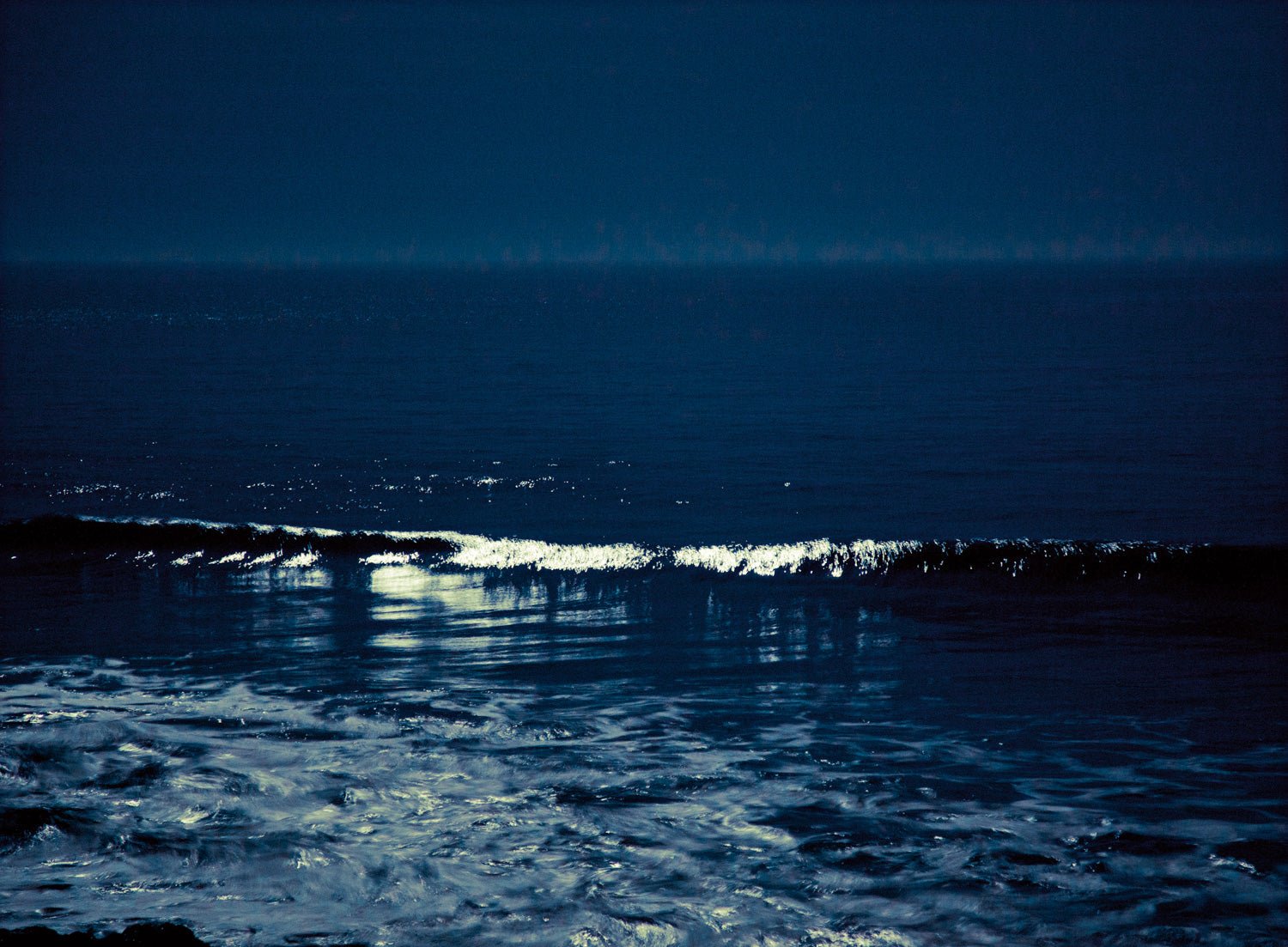 Photographie d’art d’André Wagner: Une vague claire se soulève dans l’eau bleu sombre — Moonwaves I, Portugal.