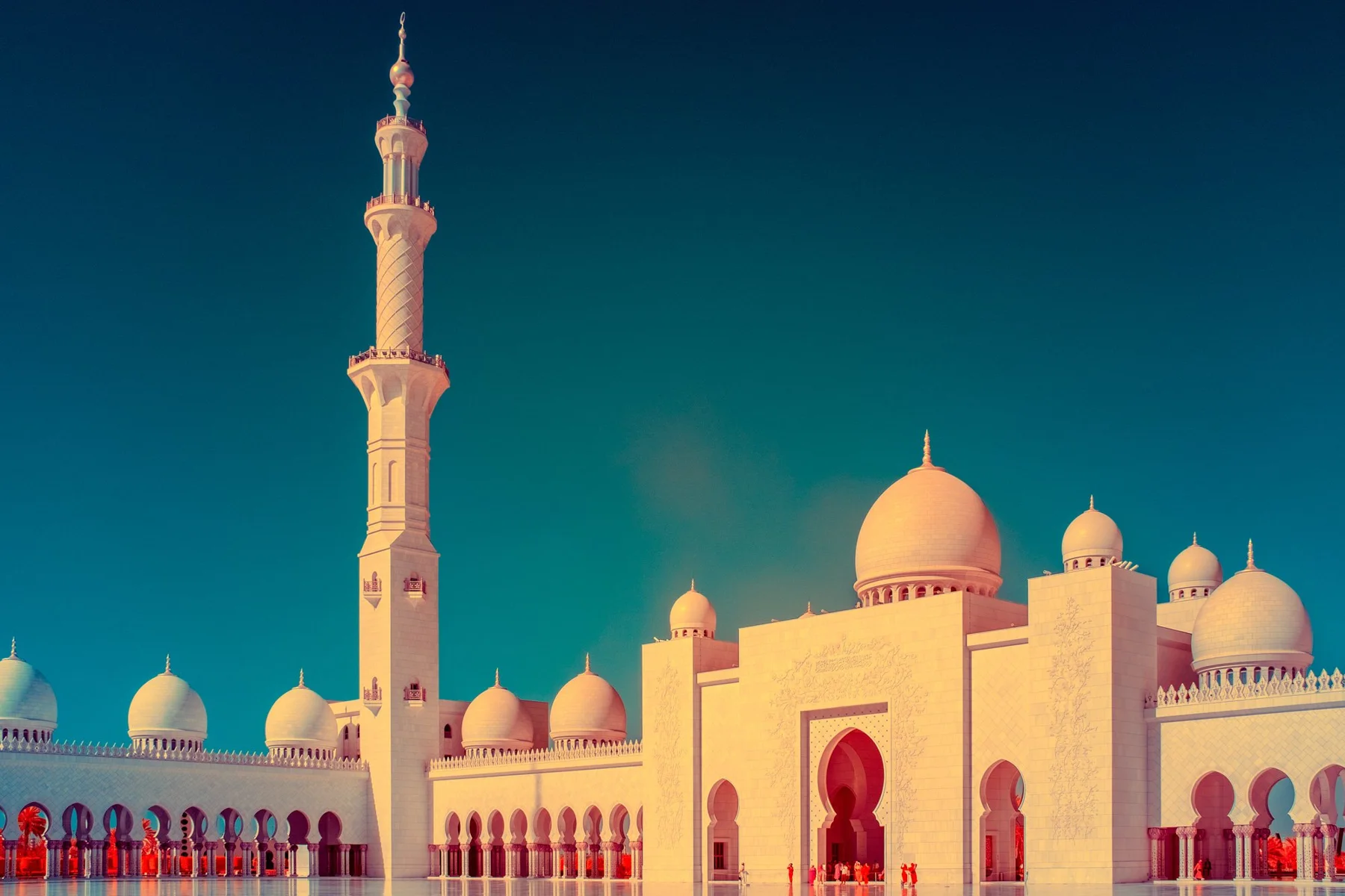Façade de mosquée avec un minaret et plusieurs coupoles.