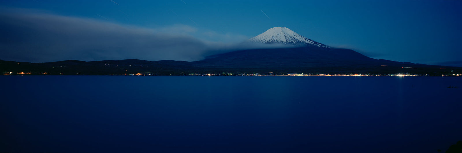 Fine art photography by André Wagner: A pale summit rises above a dark, extended shore — MT. Fuji At Night 2.