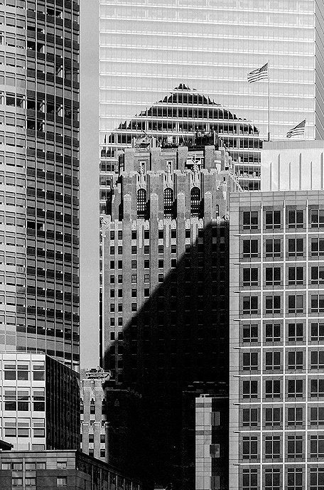 Photographie d’art d’André Wagner: Un immeuble élevé à l’apparence plus ancienne et au volume articulé se tient entre des façades strictement quadrillées — New York Silver Edition 3, USA.