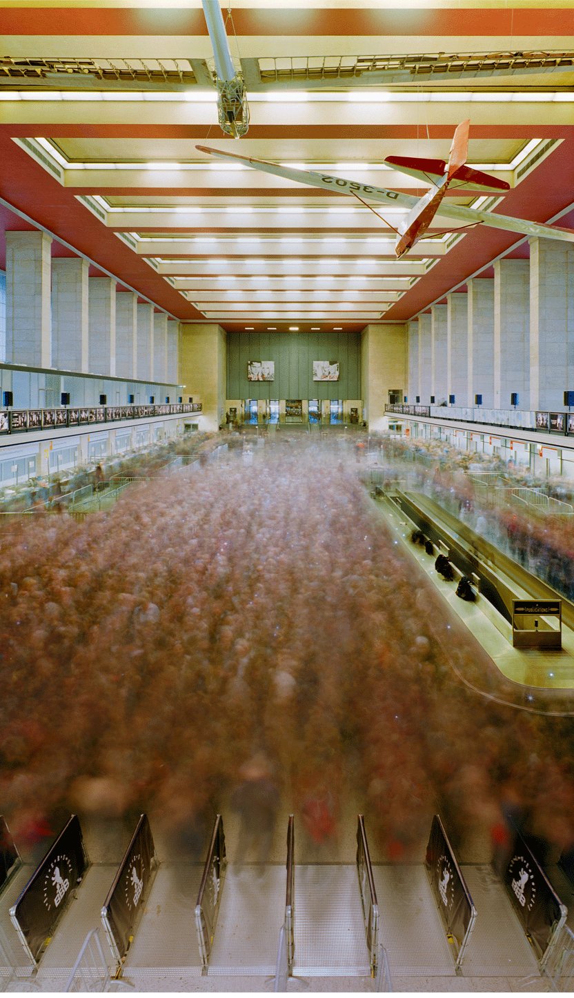 Fine art photography by André Wagner: A tall hall is divided by regular ceiling panels, red beams and side galleries — Opening, Deutschland.