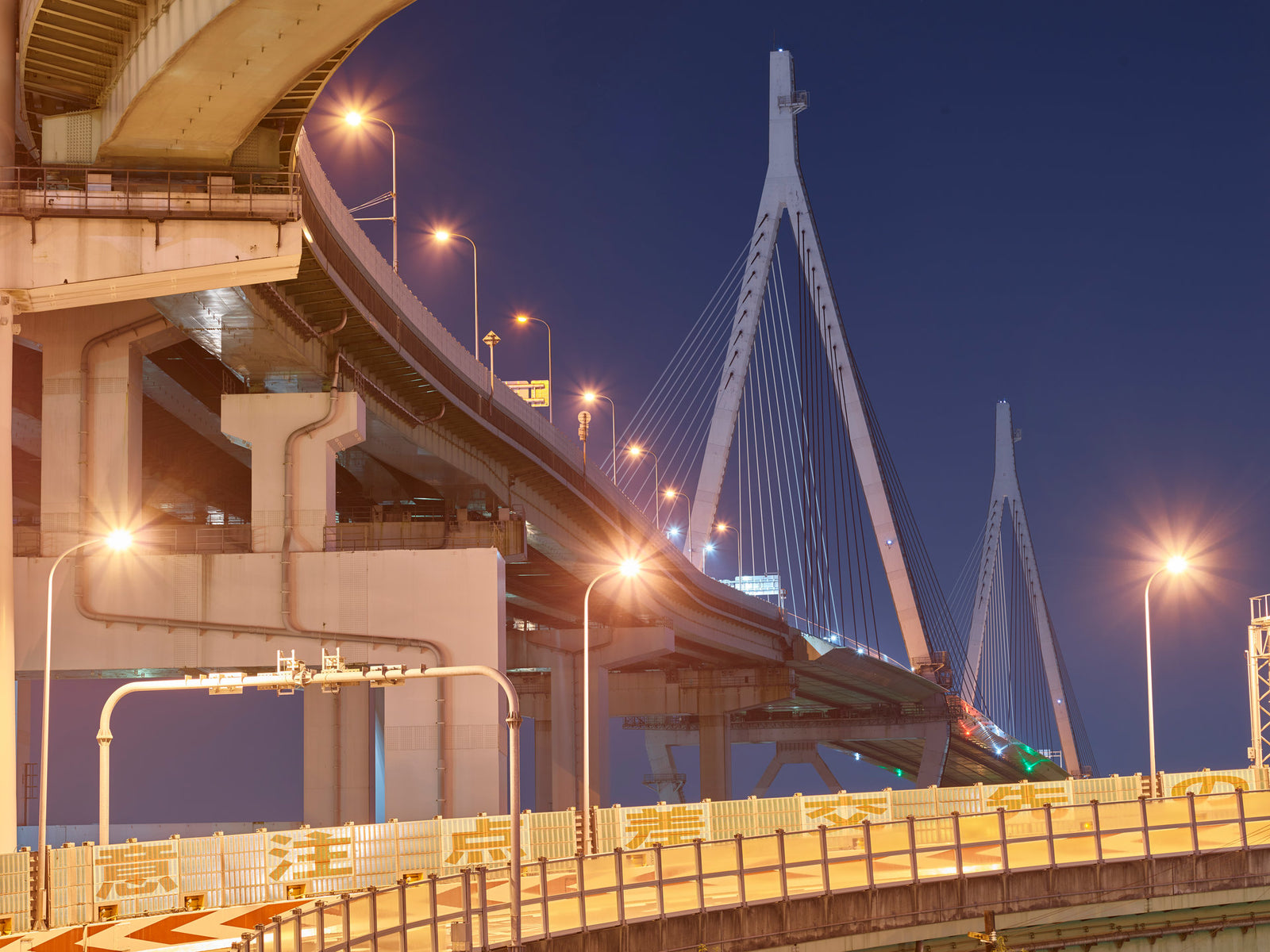 Fine art photography by André Wagner: A lit roadway curves into depth on the left — Osaka 7.