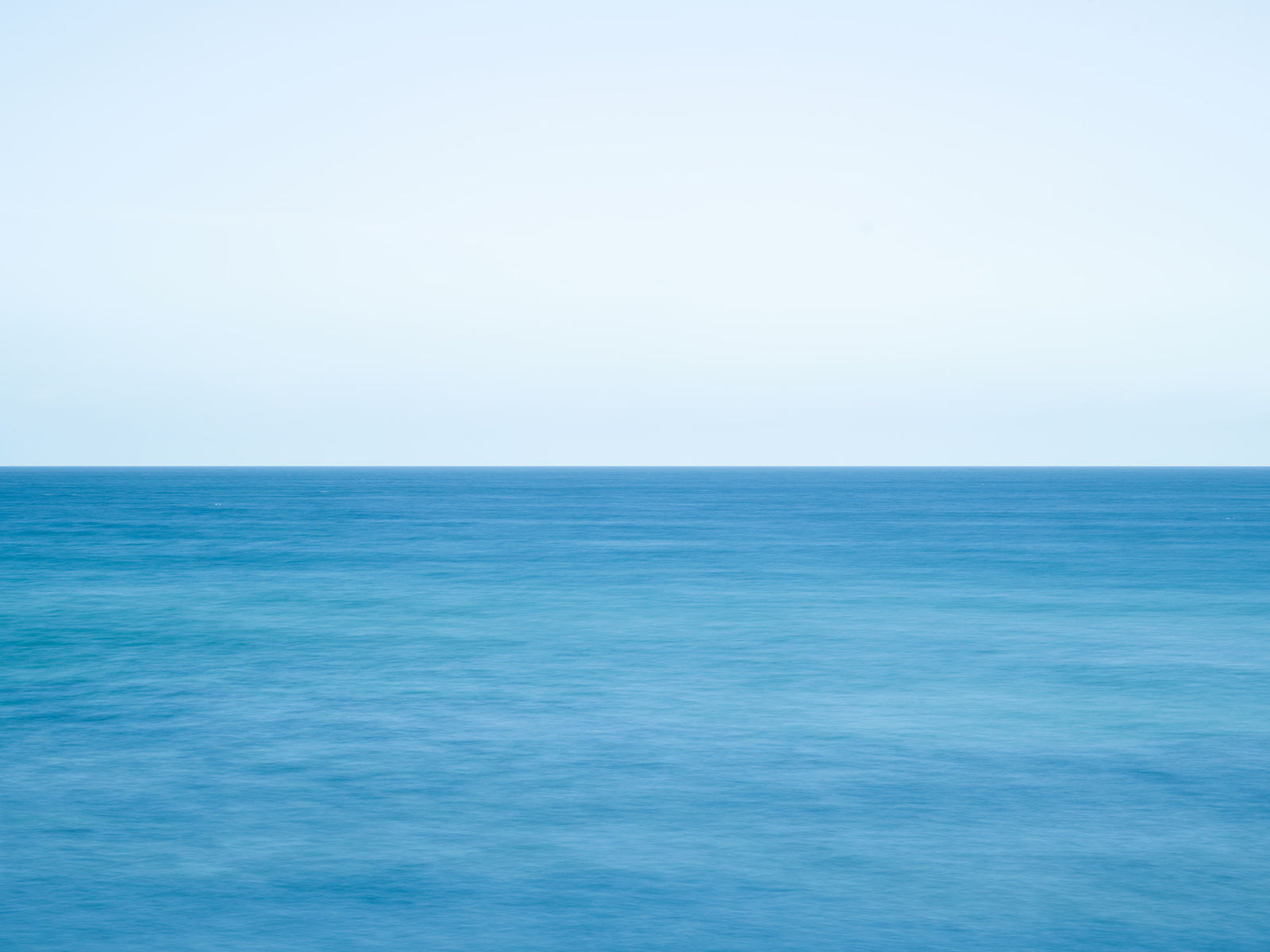 Photographie d’art d’André Wagner: Une ligne d’horizon droite partage la photographie entre un ciel clair et une eau bleu turquoise — Ostsee 4, Deutschland.