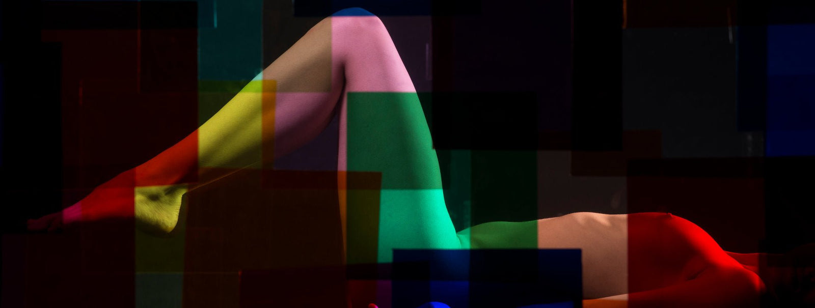 Fine art photography by André Wagner: A reclining body extends through a very wide dark frame — Paula IV.