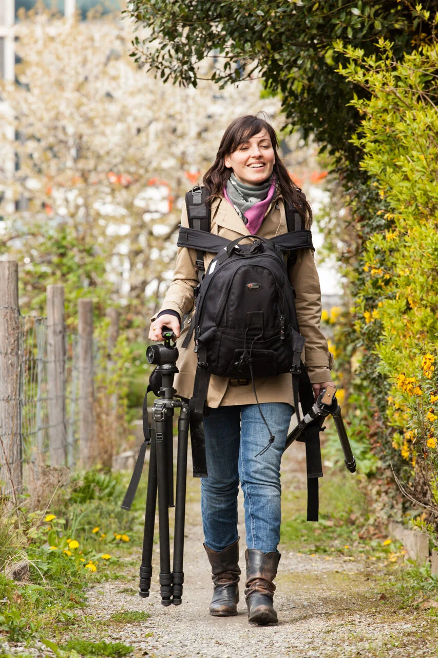 Personne avec du matériel photographique sur un chemin bordé de végétation