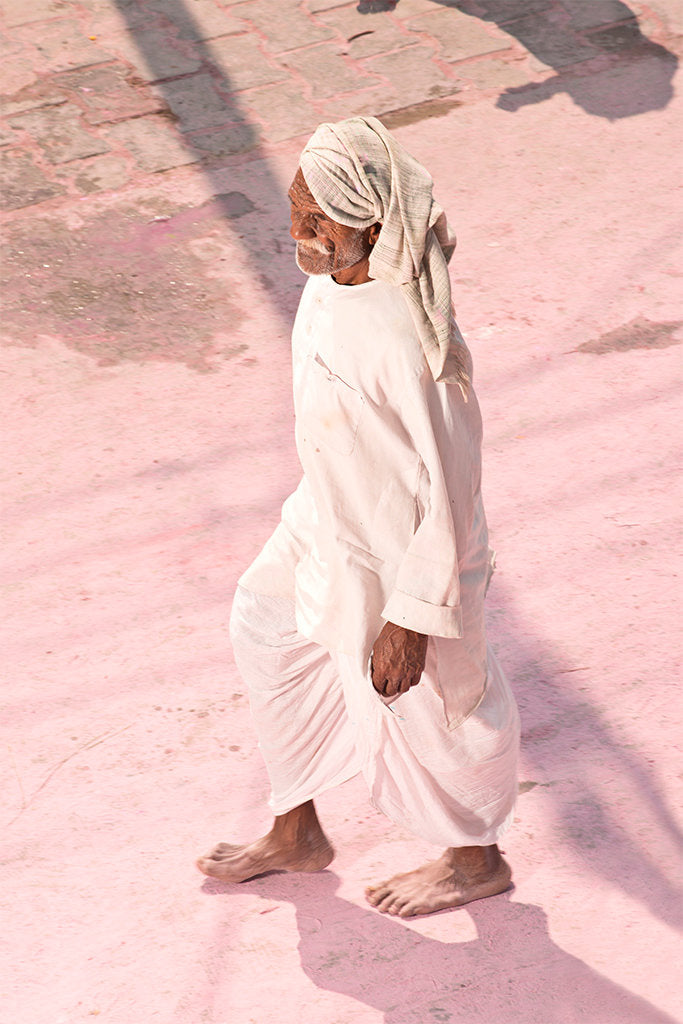 Photographie d’art d’André Wagner: Un homme presque entièrement vêtu de blanc avance sur un sol rose clair — Pilgrim on Purple Dust 5, Indien.