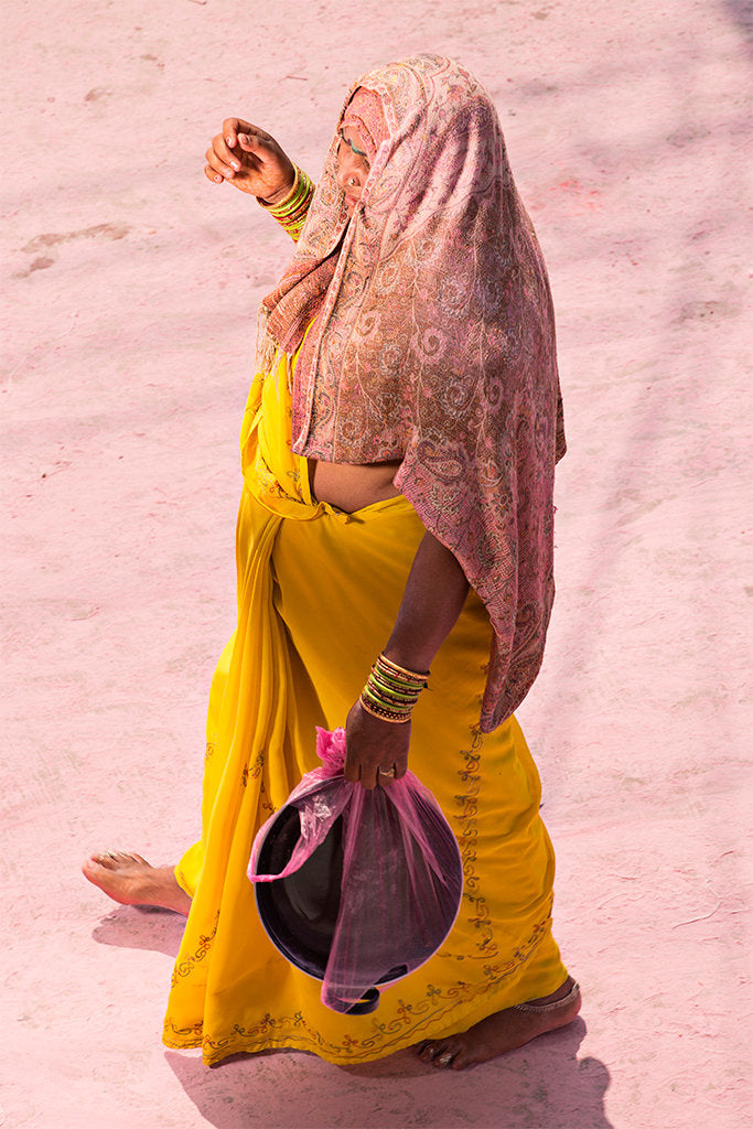 Photographie d’art d’André Wagner: Une femme seule vêtue de jaune se détache comme une figure colorée nette sur le sol rose — Pilgrim on Purple Dust 7, Indien.