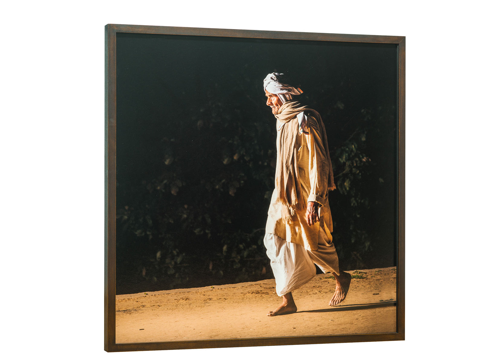 Photographie d’art d’André Wagner: Un homme seul, vêtu de clair, marche vers la gauche devant un feuillage sombre — Pilgrims at govardhan 4, Indien.