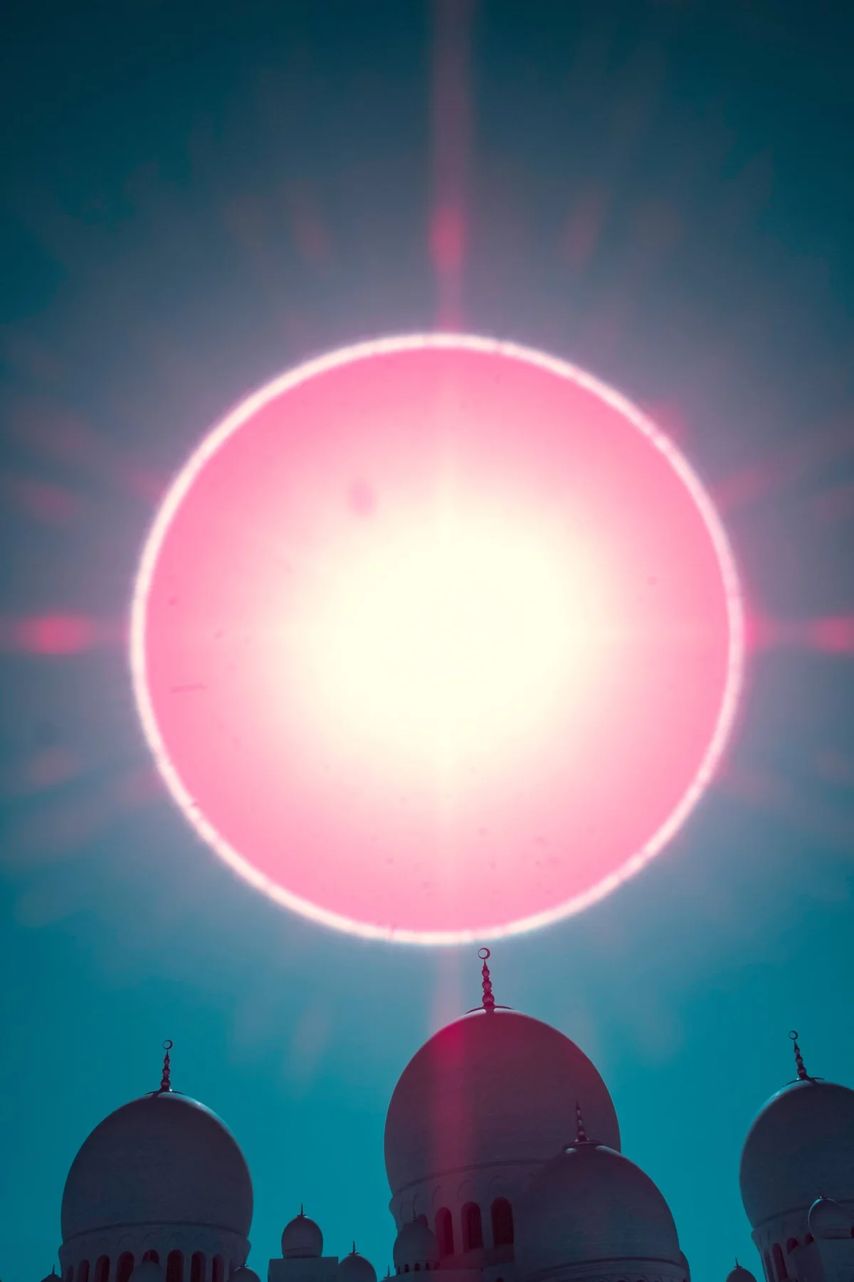 Cercle de lumière rose au-dessus des coupoles d’une mosquée.