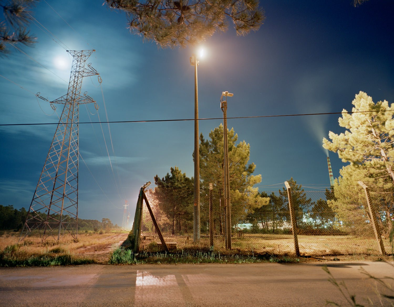 Fine art photography by André Wagner: A fence crosses a night landscape, interrupted by vertical posts — Ring Fence, Portugal.