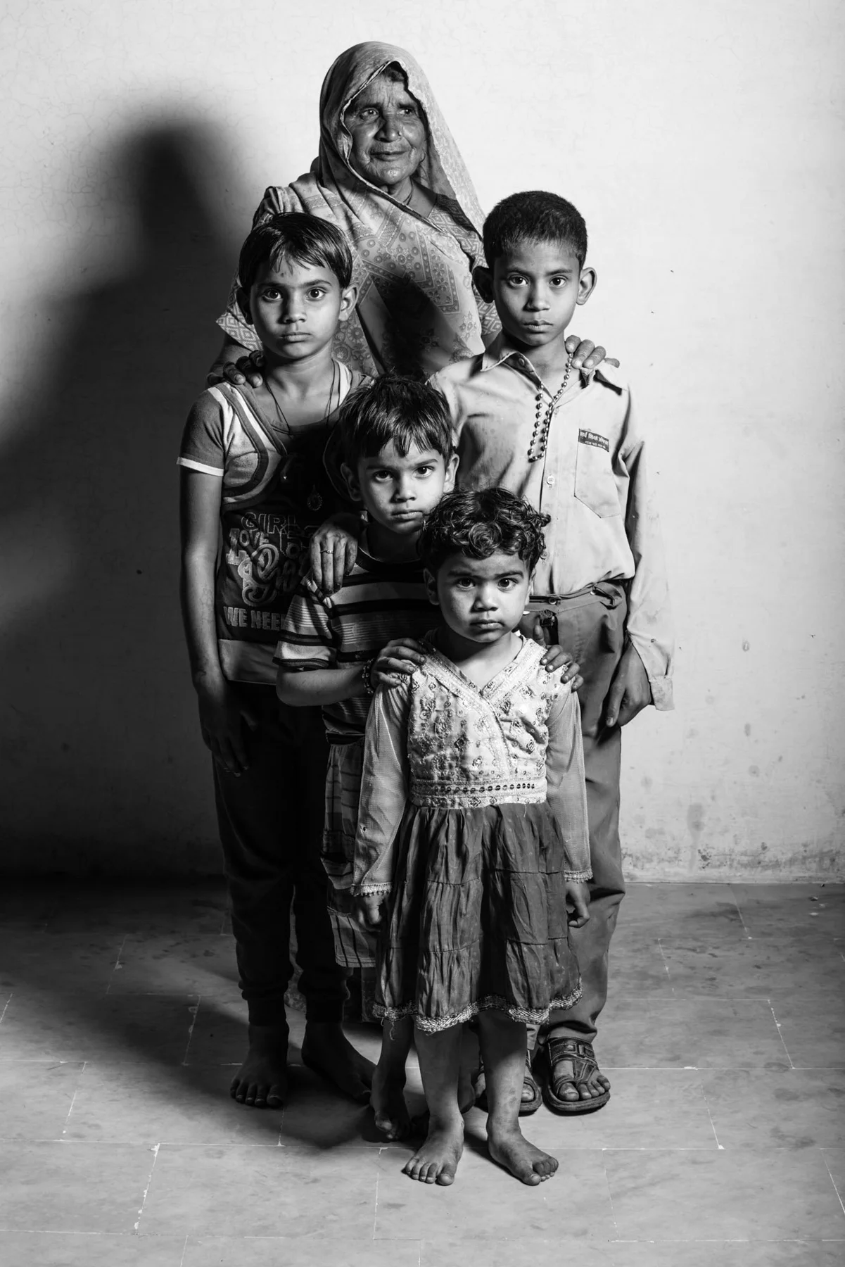 Black and white group portrait of a woman with several children in front of a wall.