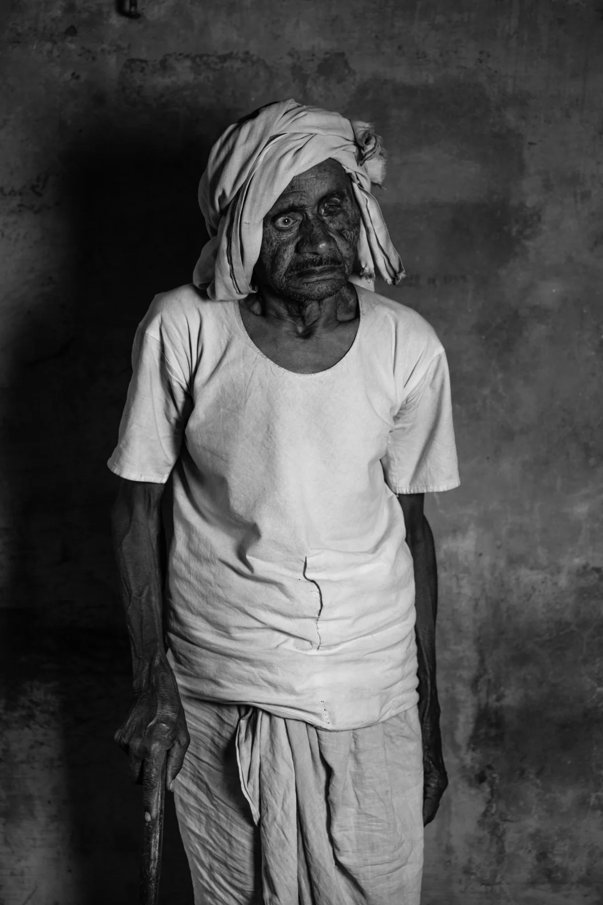 Black and white portrait of a man in a white shirt and turban.