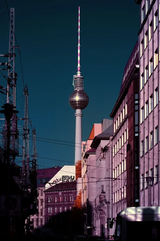 Photographie d’art infrarouge d’André Wagner: La tour de télévision de Berlin s’élève entre l’arête sombre d’un bâtiment à gauche et une longue façade vitrée à droite — Signal and Symbol.