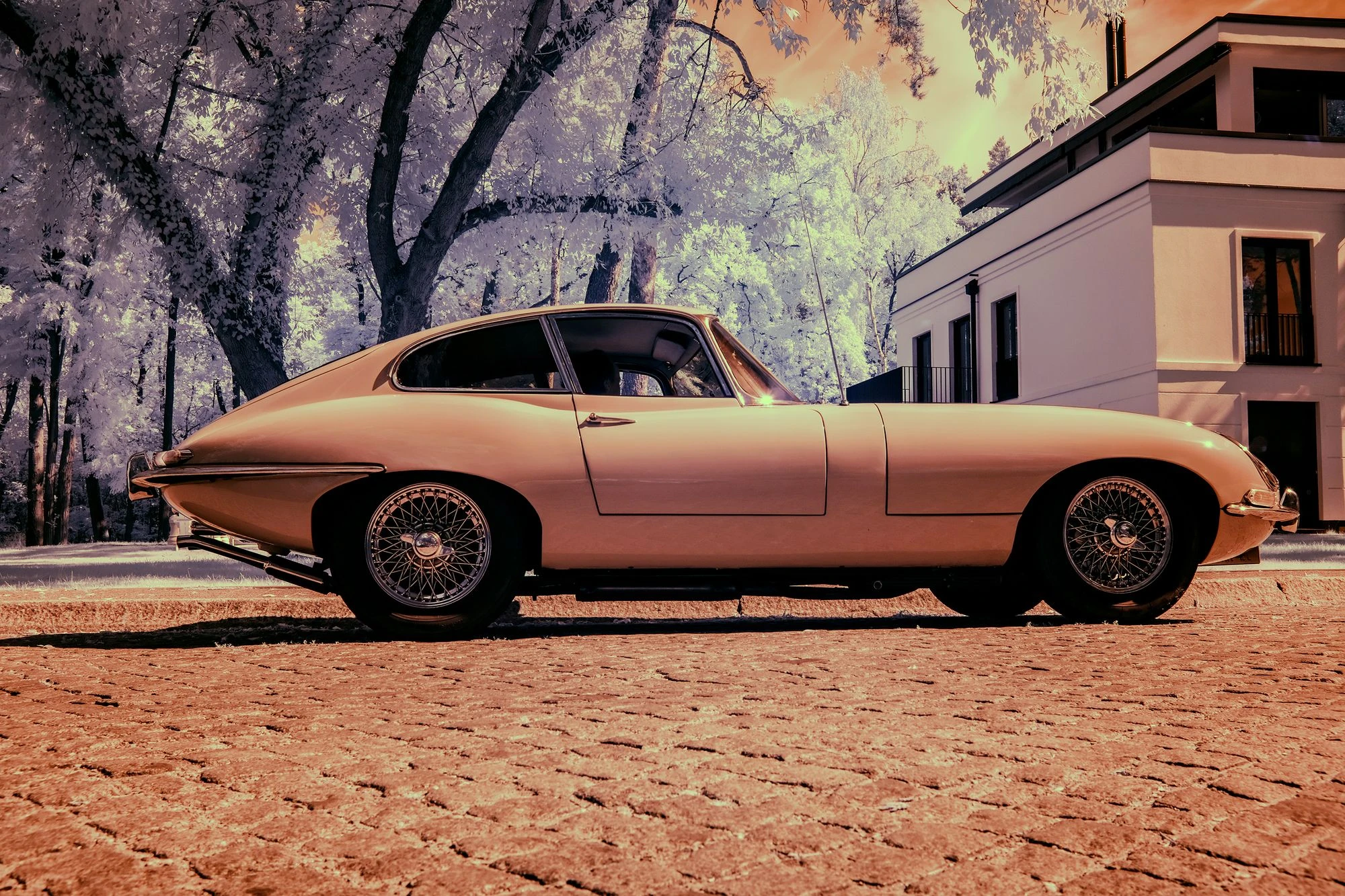 Photographie d’art infrarouge d’André Wagner: Une Jaguar claire est vue de profil dans une cour pavée — Silent Velocity, 1966.