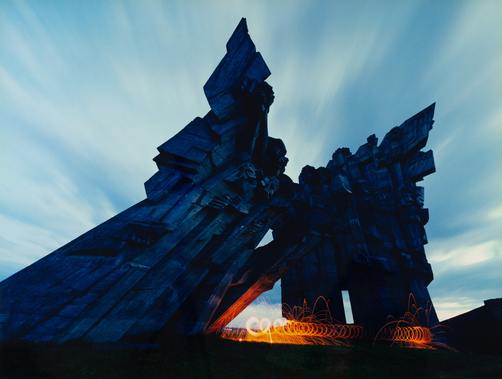 Fine art photography by André Wagner: Dark angular structures rise in oblique directions against pale streaked sky — Softice on fire, Litauen.