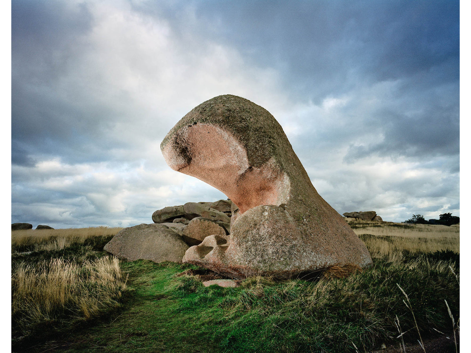 Fine art photography by André Wagner: A large stone stands in open landscape with its upper portion bent forward — Story of wind, Frankreich.