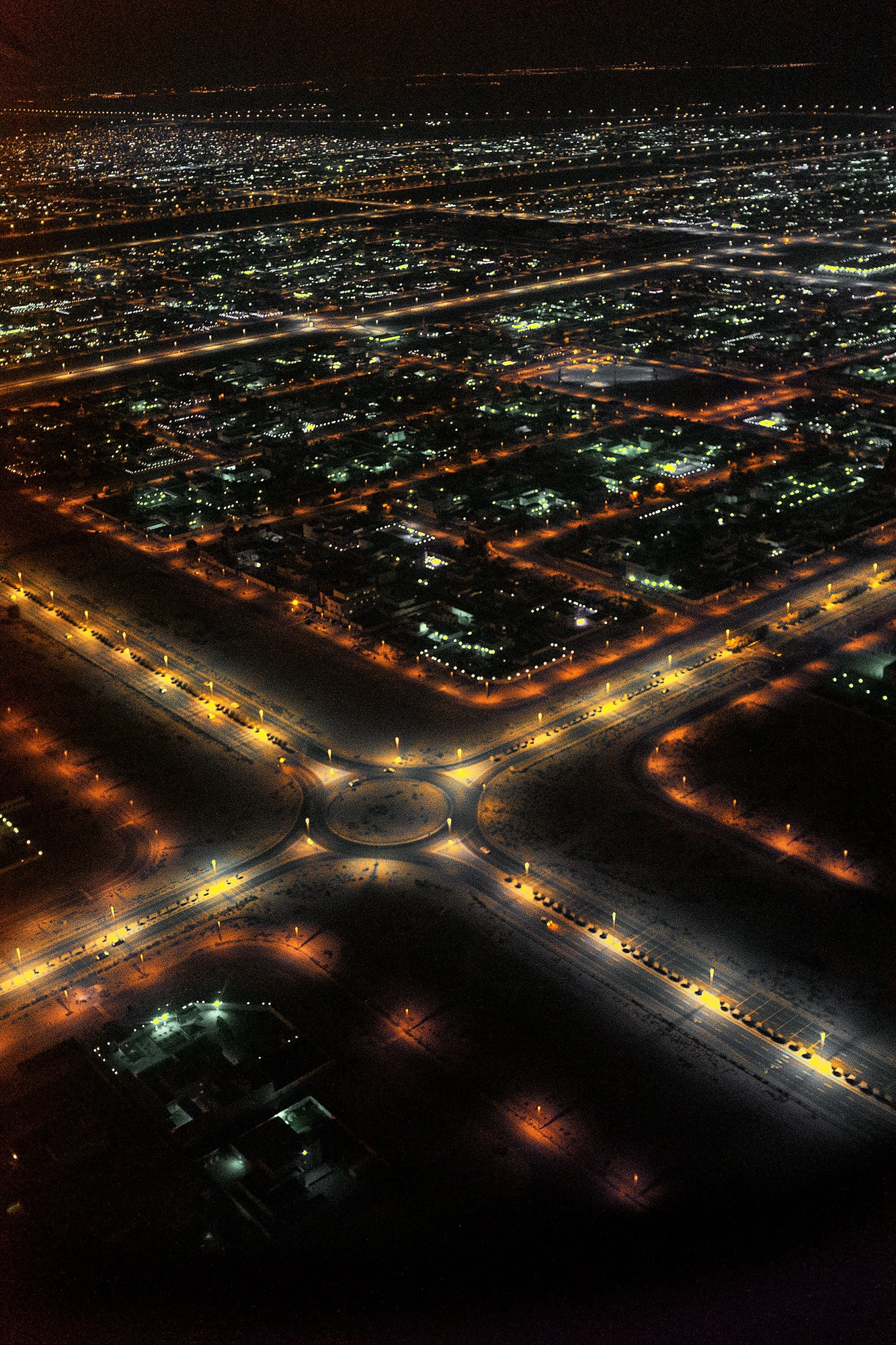 Photographie d’art infrarouge d’André Wagner: Vue d’en haut, la ville nocturne apparaît comme un réseau de petits points lumineux et de longues lignes de rues — Streets of the Emirates.